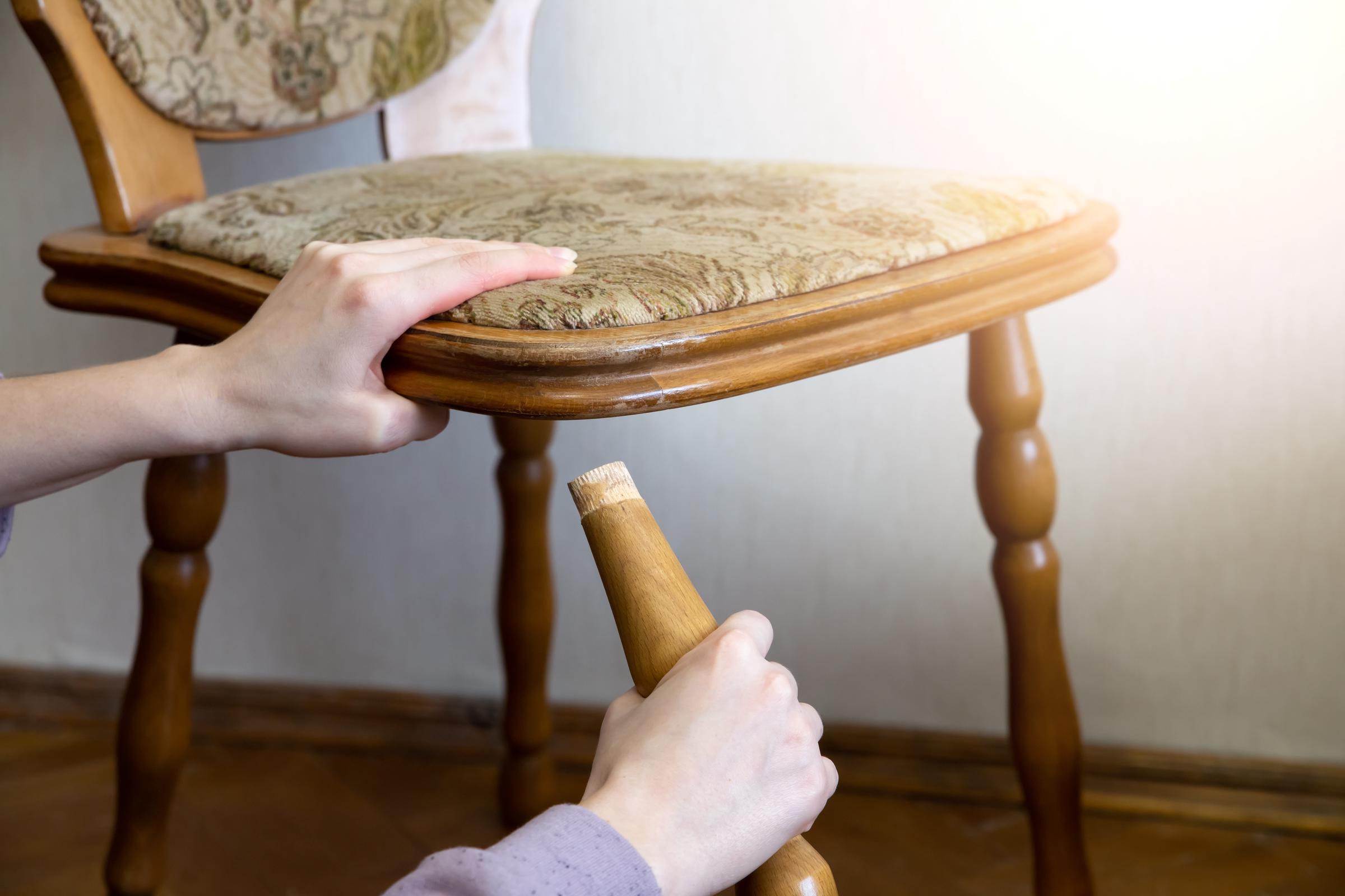 A close-up shot of a woman holding the leg of a broken chair | Source: Shutterstock
