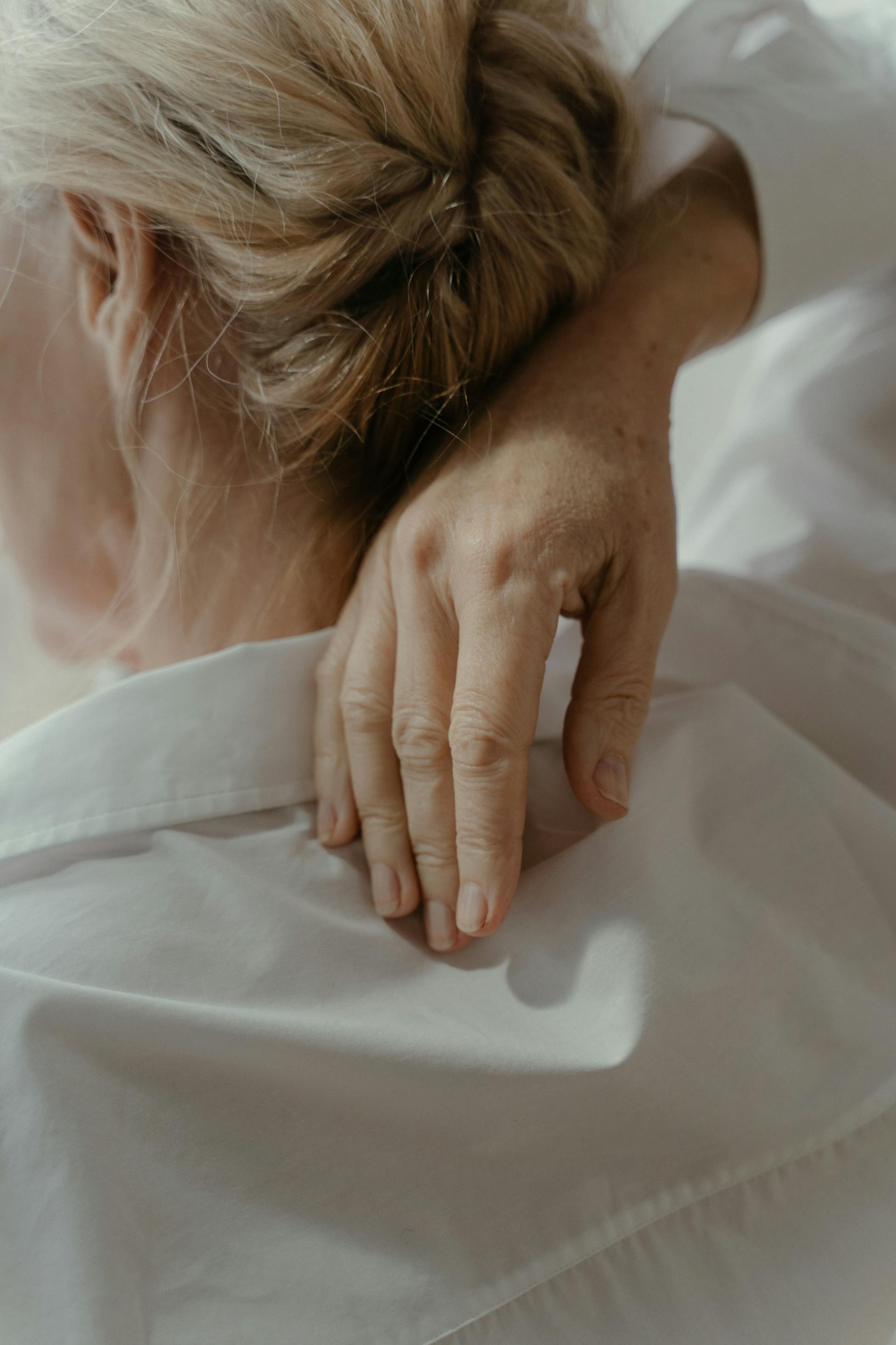 An elderly woman touching her back with one hand | Source: Pexels