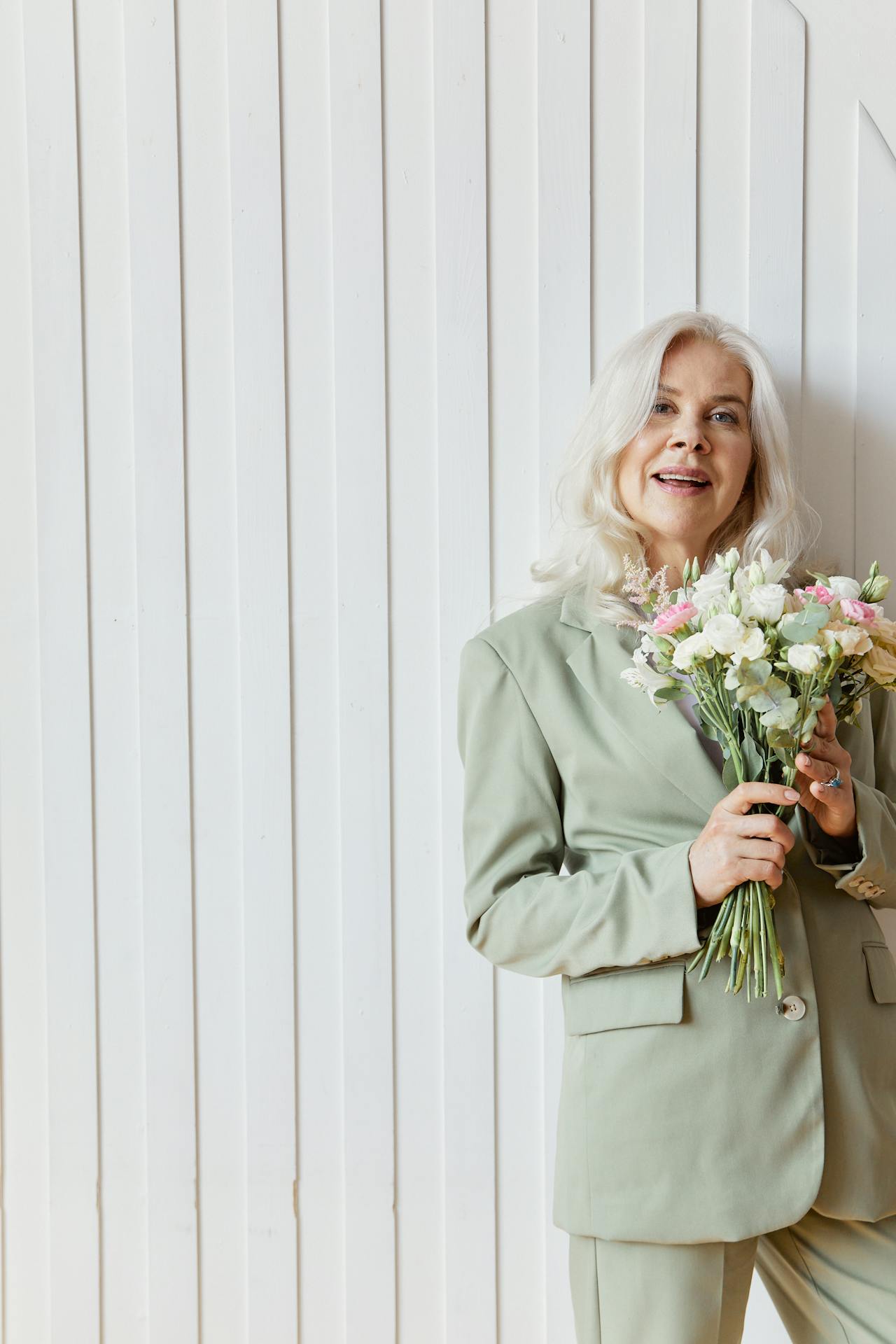 A smiling older woman holding a bouquet of flowers | Source: Pexels
