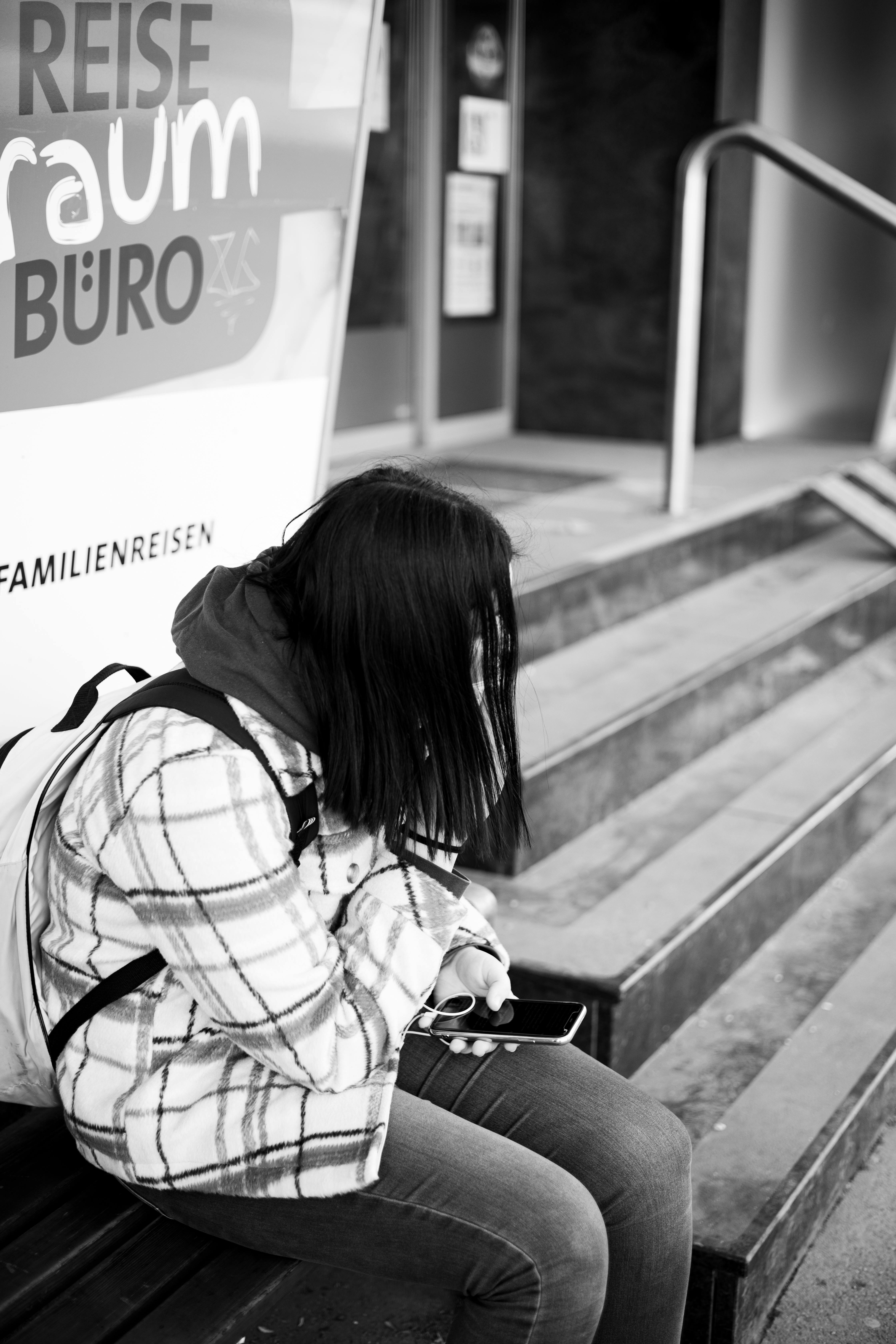 A girl sitting on a bench holding her phone | Source: Pexels