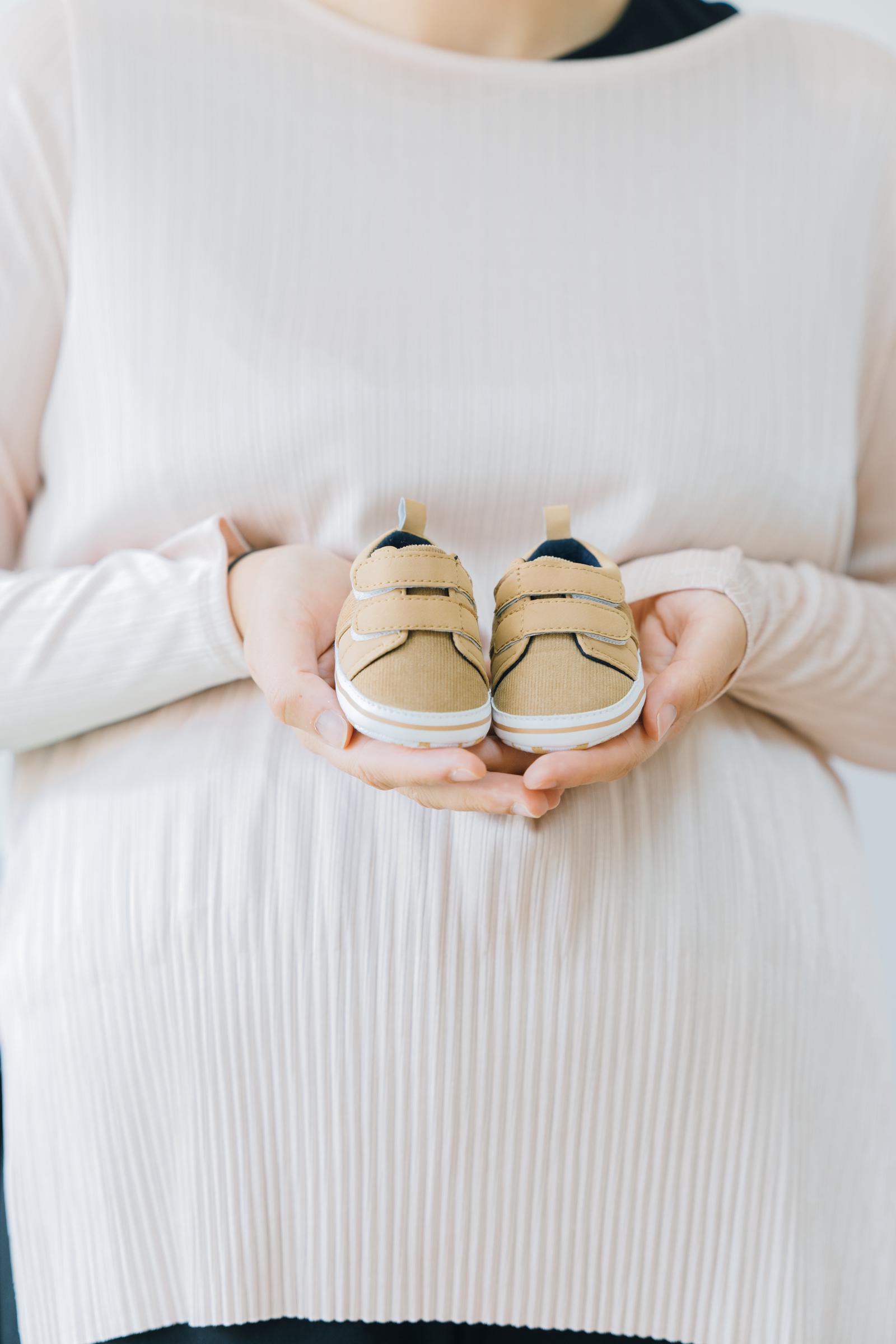 A woman holding tiny baby shoes | Source: Freepik