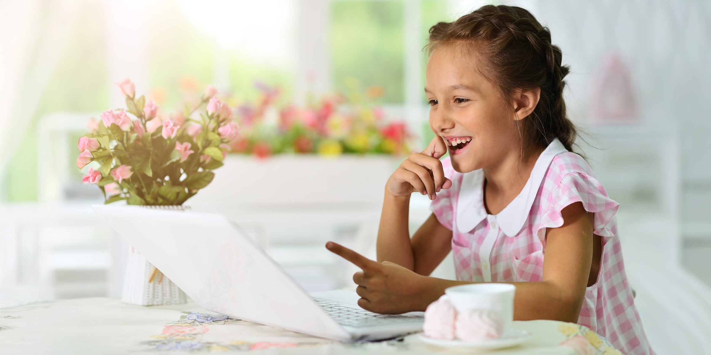 A smiling girl pointing at a laptop screen | Source: Shutterstock