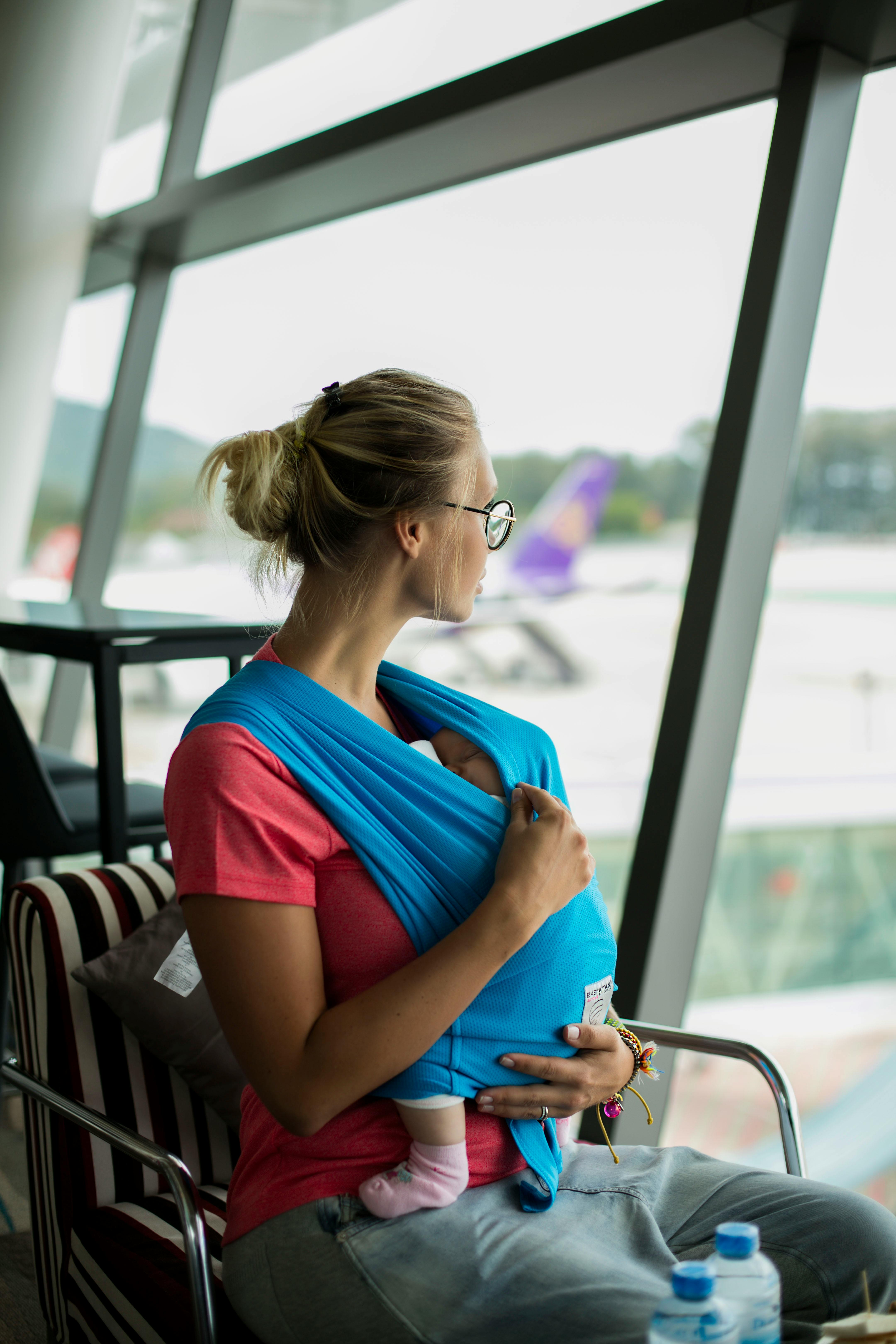 Blonde woman with baby looking through window at an airport | Source: Getty Images
