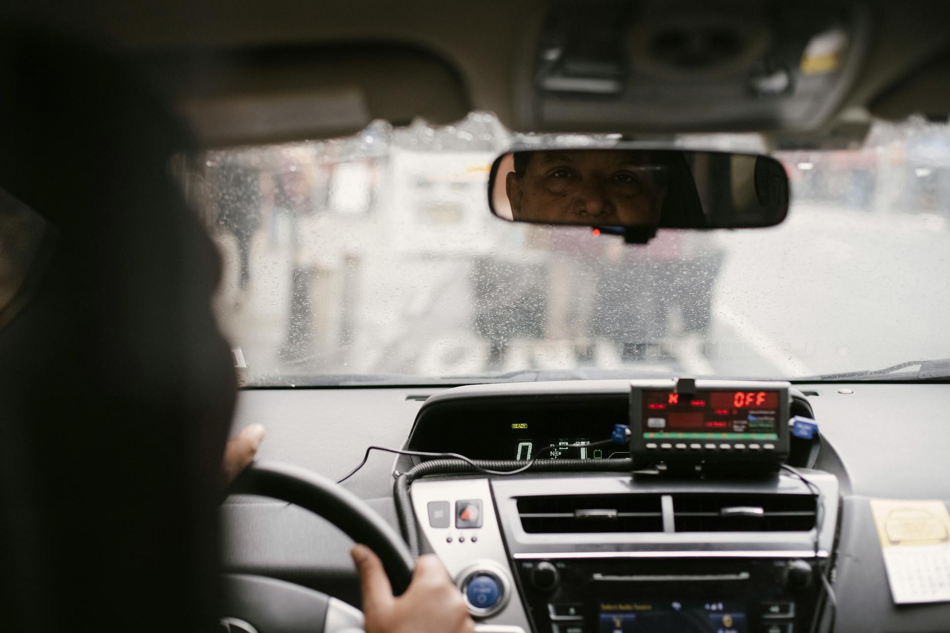 A taxi driver glancing at someone in the rearview mirror | Source: Pexels