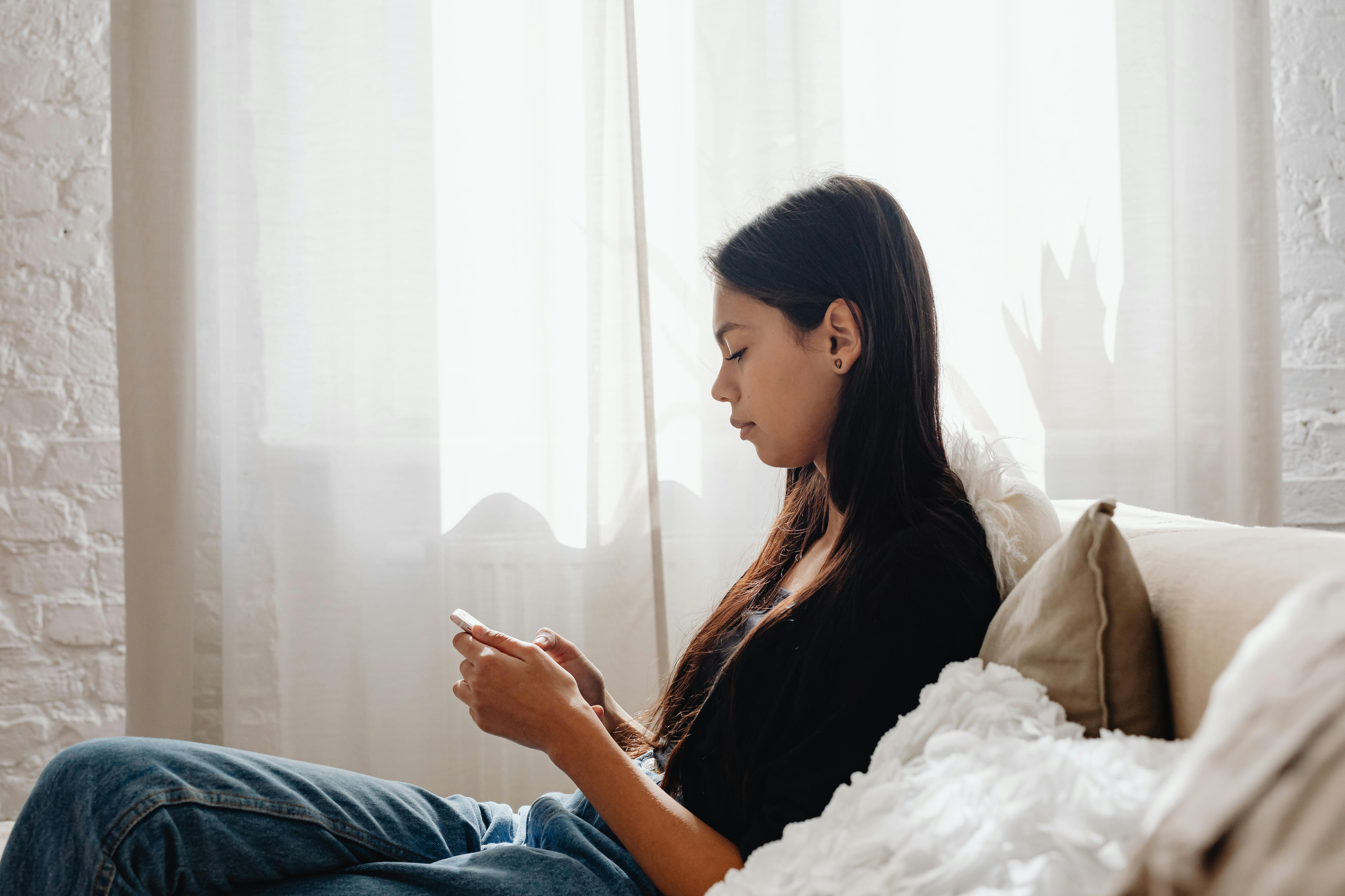 A teenage girl sitting on a couch | Source: Pexels