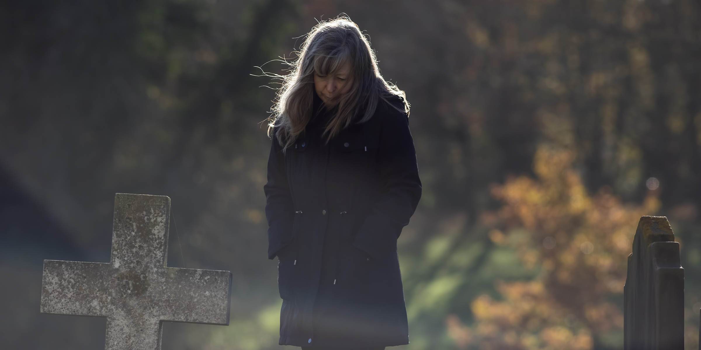 A grieving woman near a headstone ⏐ Source: Shutterstock