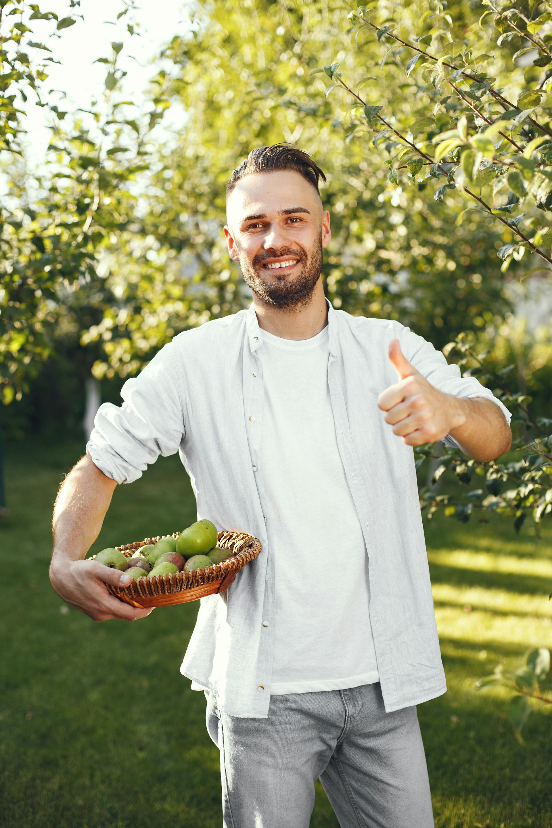 A man standing in his garden holding a basket of fruits | Source: Pexels