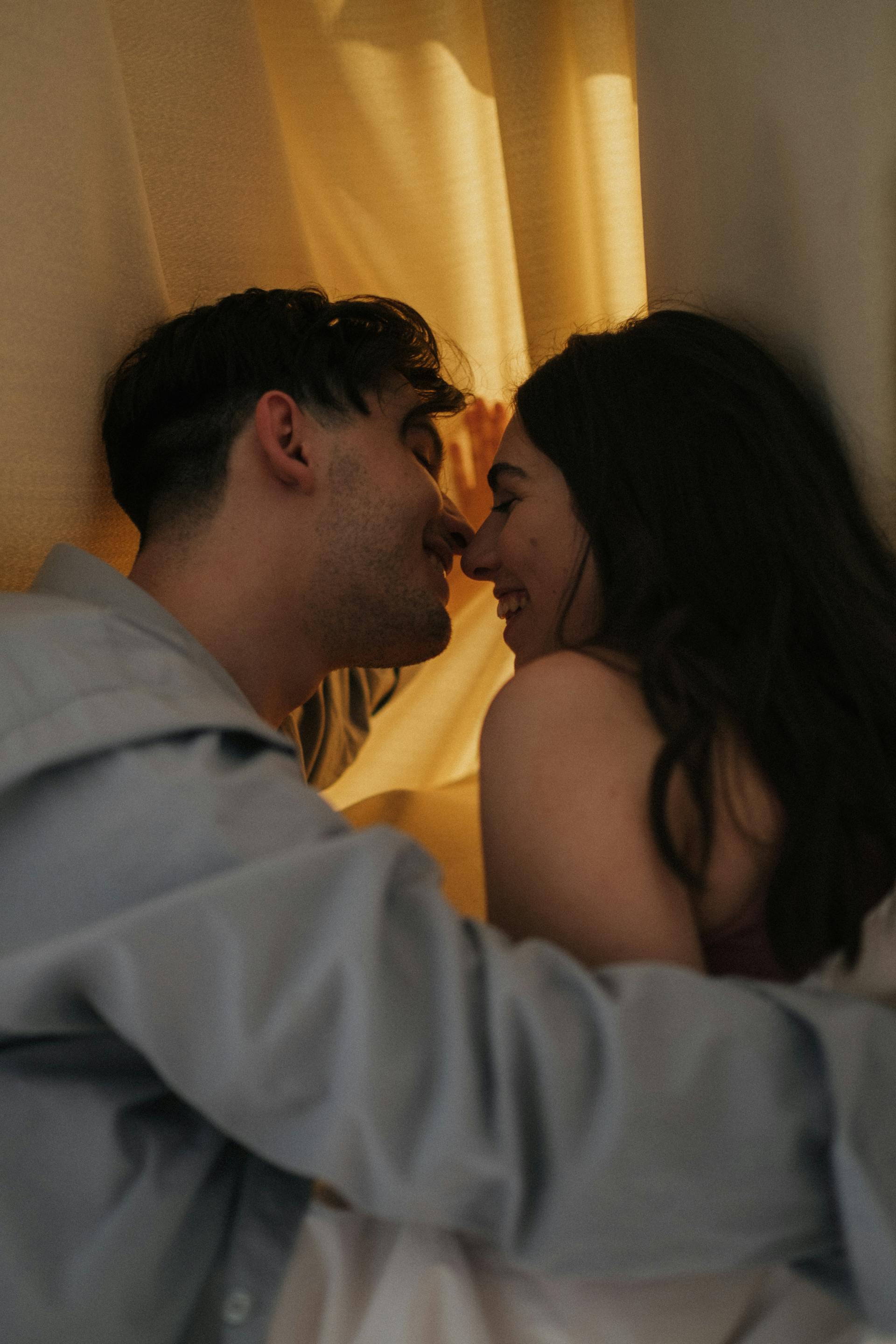 A happy couple kissing behind a drape | Source: Pexels