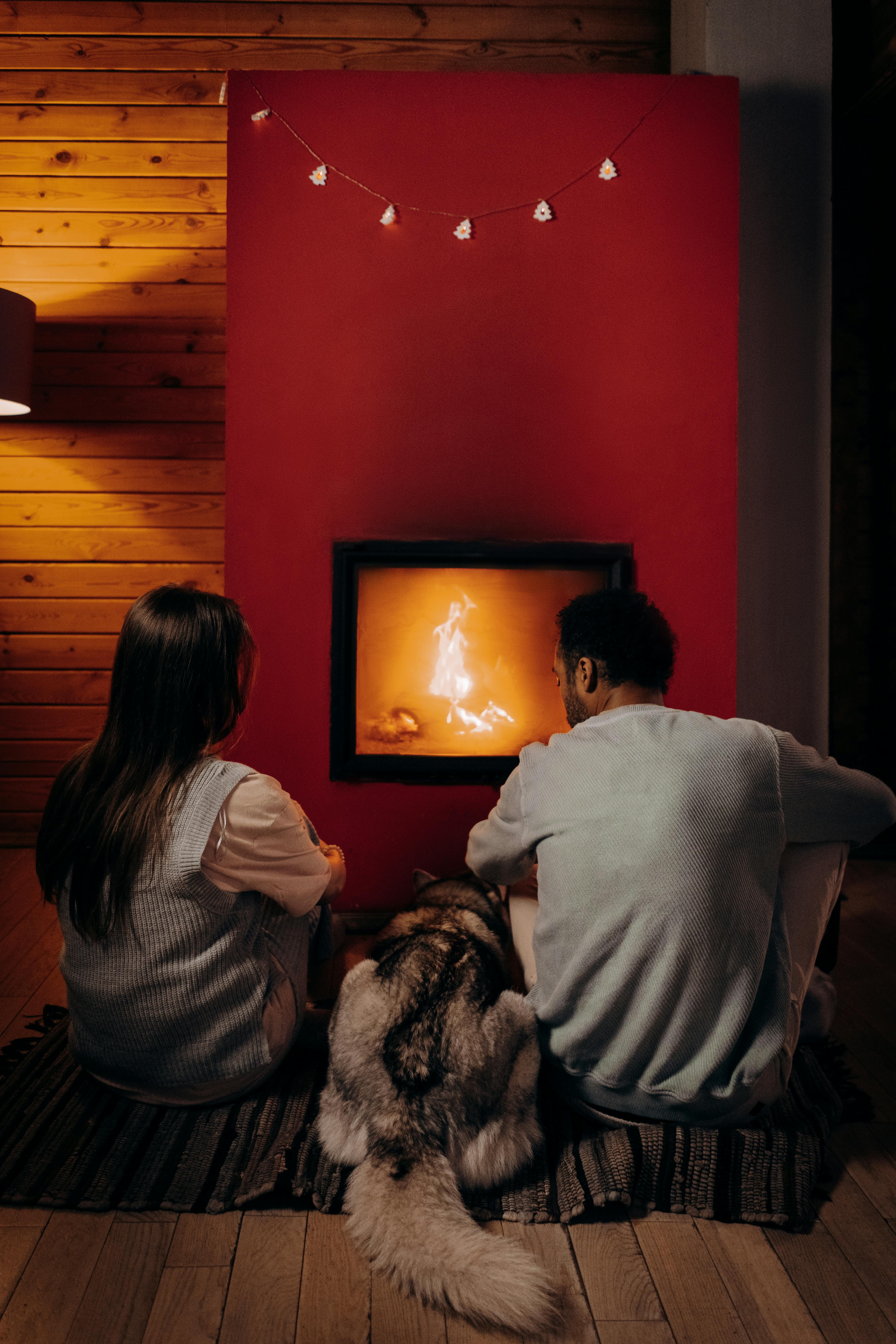 A couple sitting near a fireplace with their dog | Source: Pexels