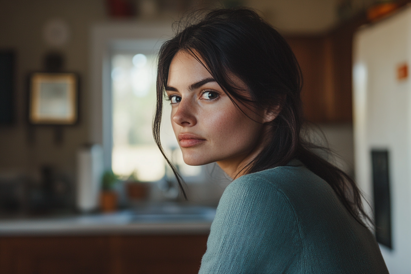 Una mujer seria sentada a la mesa de la cocina | Fuente: Midjourney