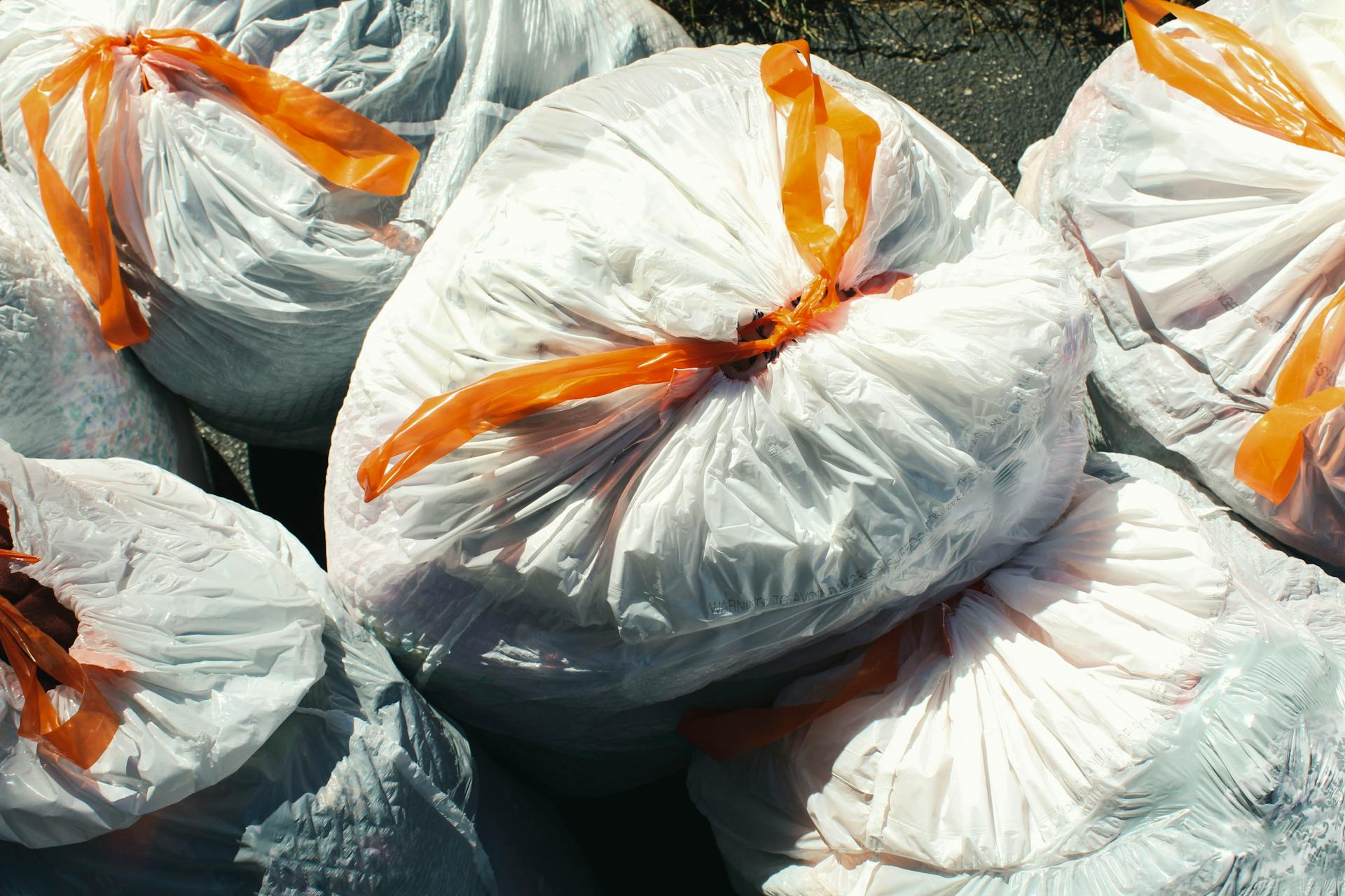Several garbage bags tied up with orange ribbon | Source: Pexels