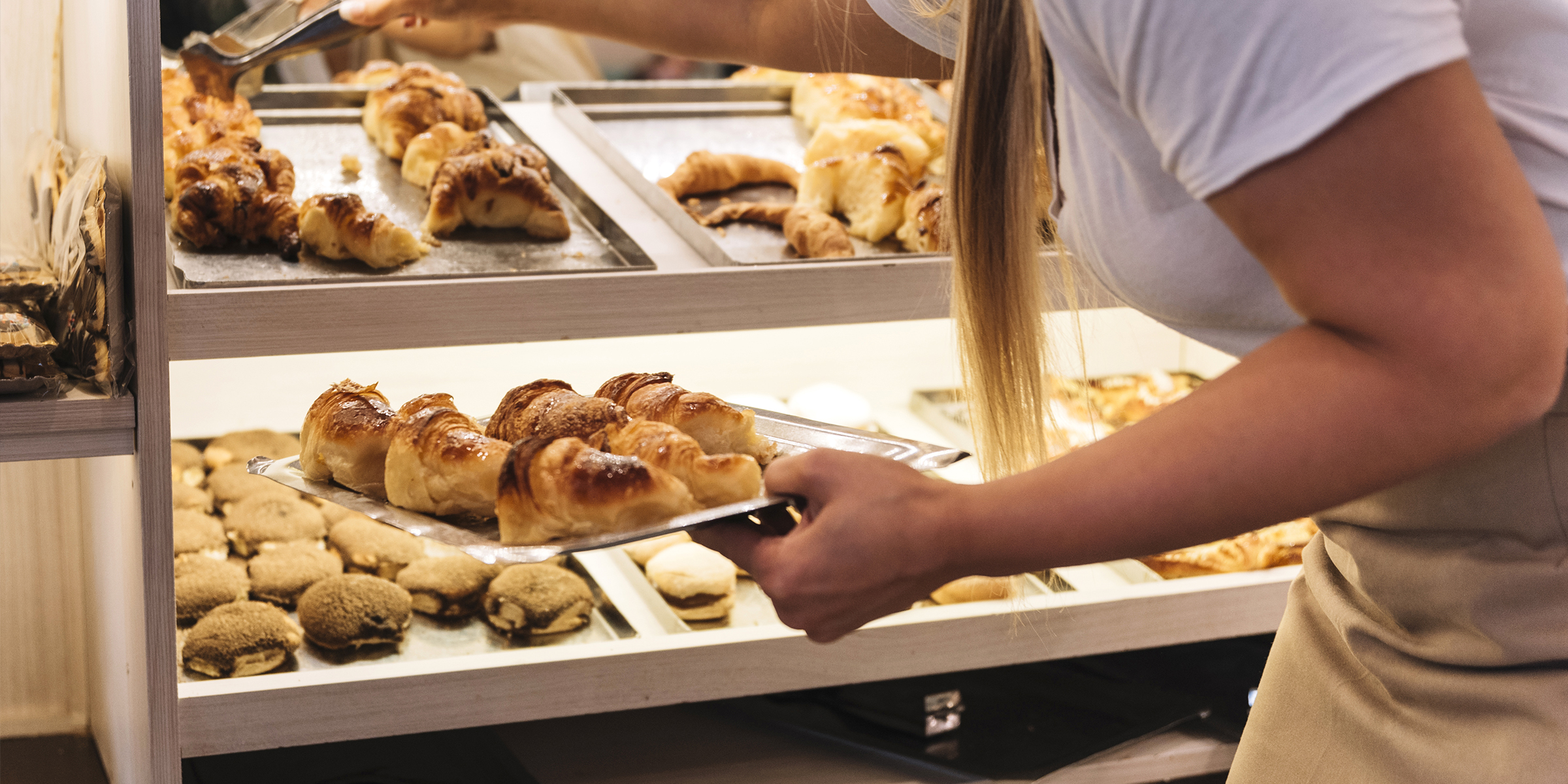A woman stocking a bakery display case | Source: Freepik