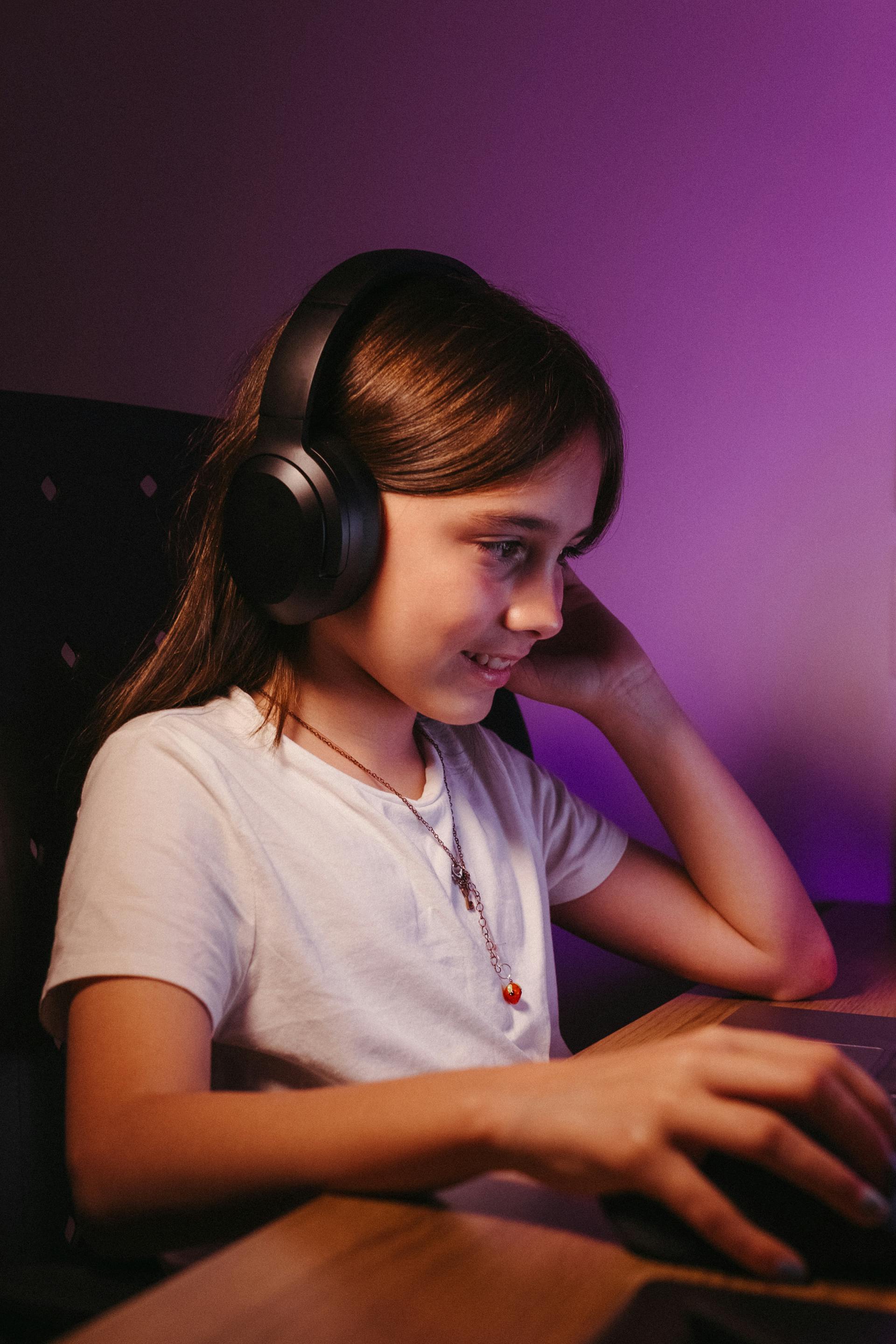 A teen girl using a headset and computer | Source: Pexels