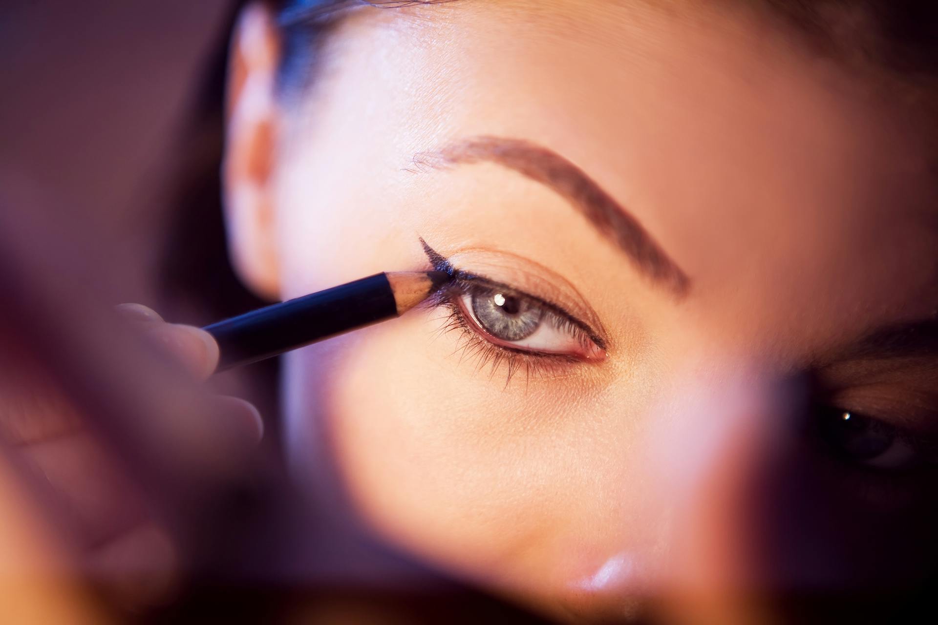 A woman applying eye liner | Source: Pexels