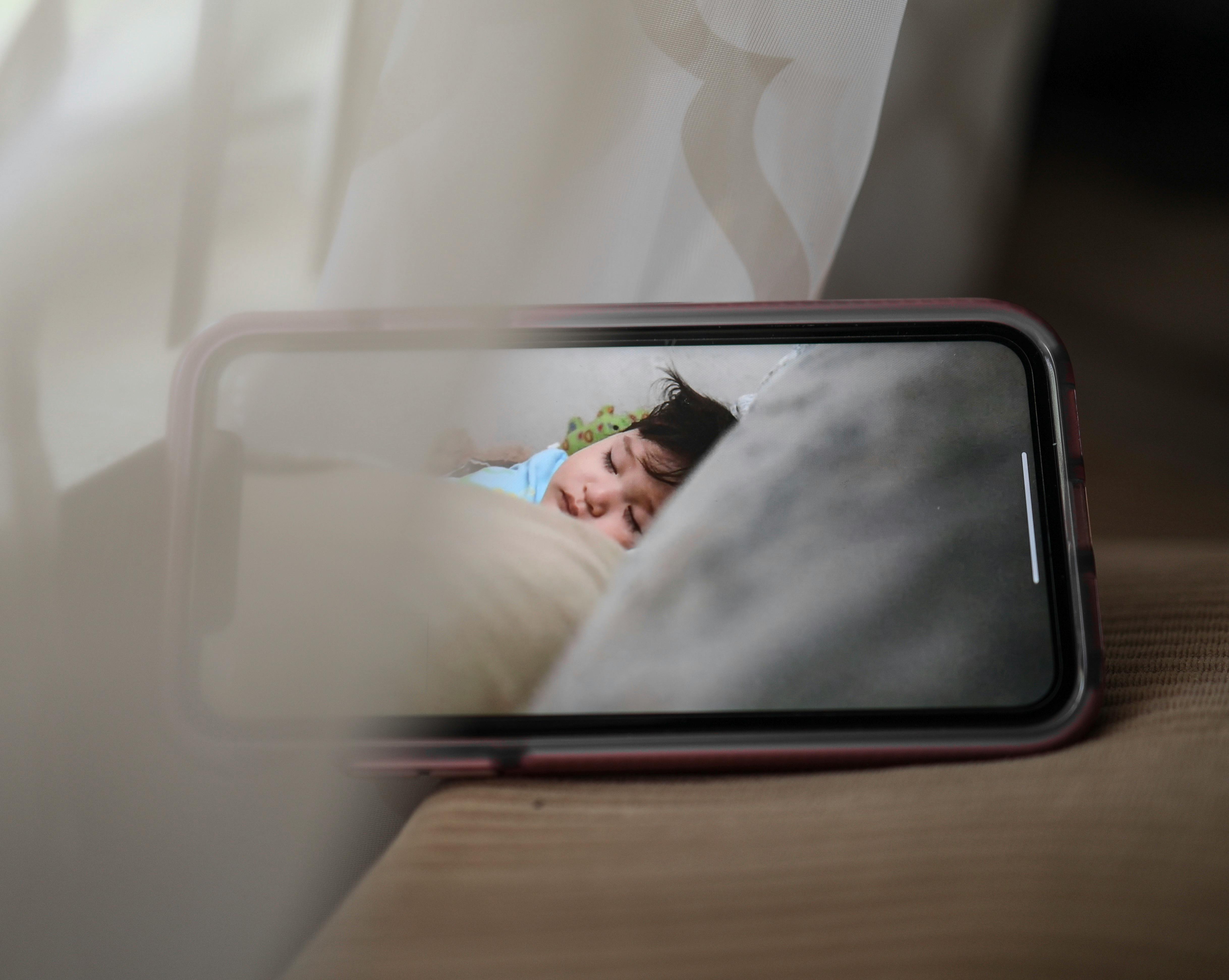 Mobile phone screen displaying a baby sleeping | Source: Pexels