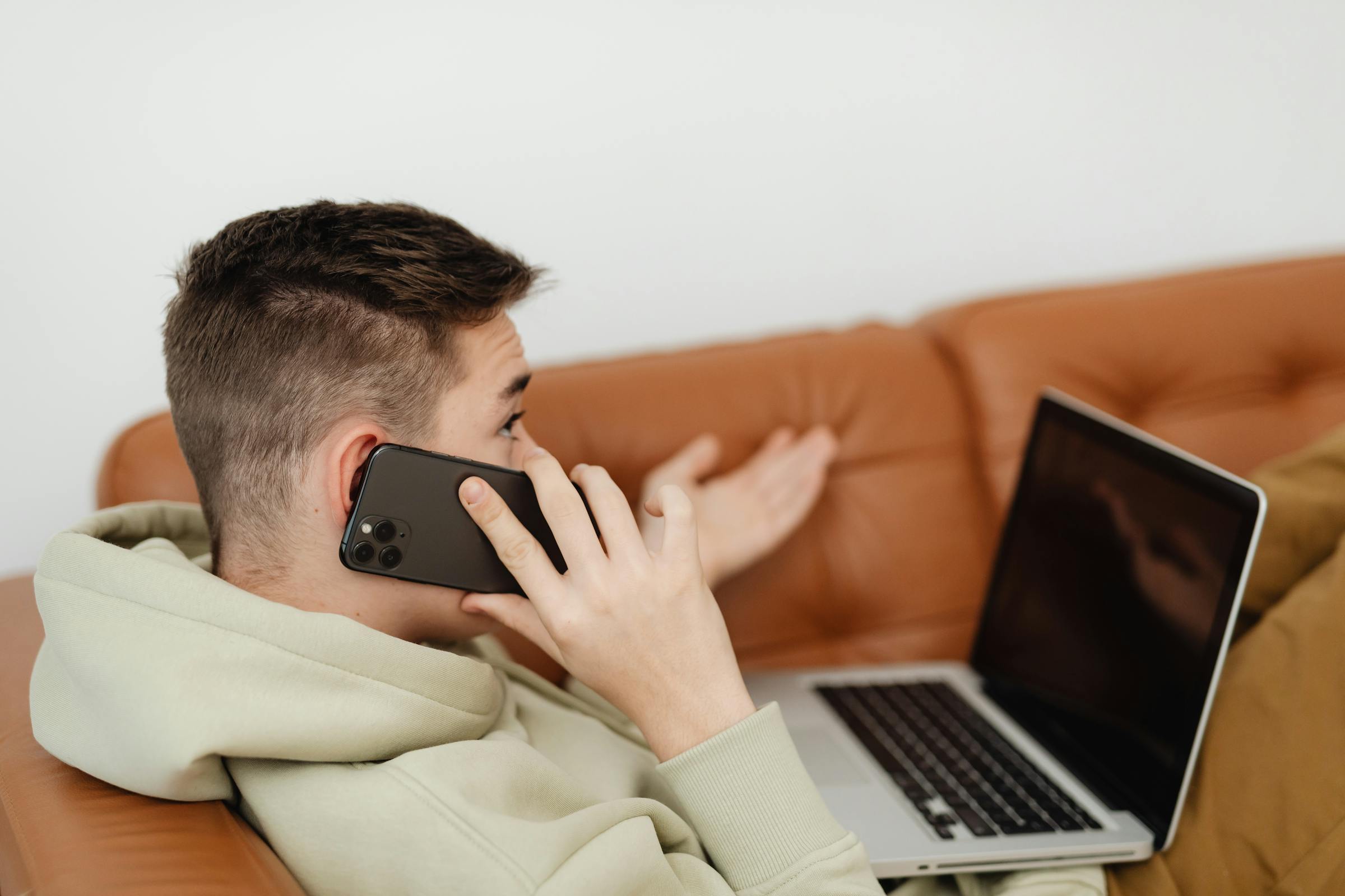 A teen boy on a couch talking on the phone | Source: Pexels