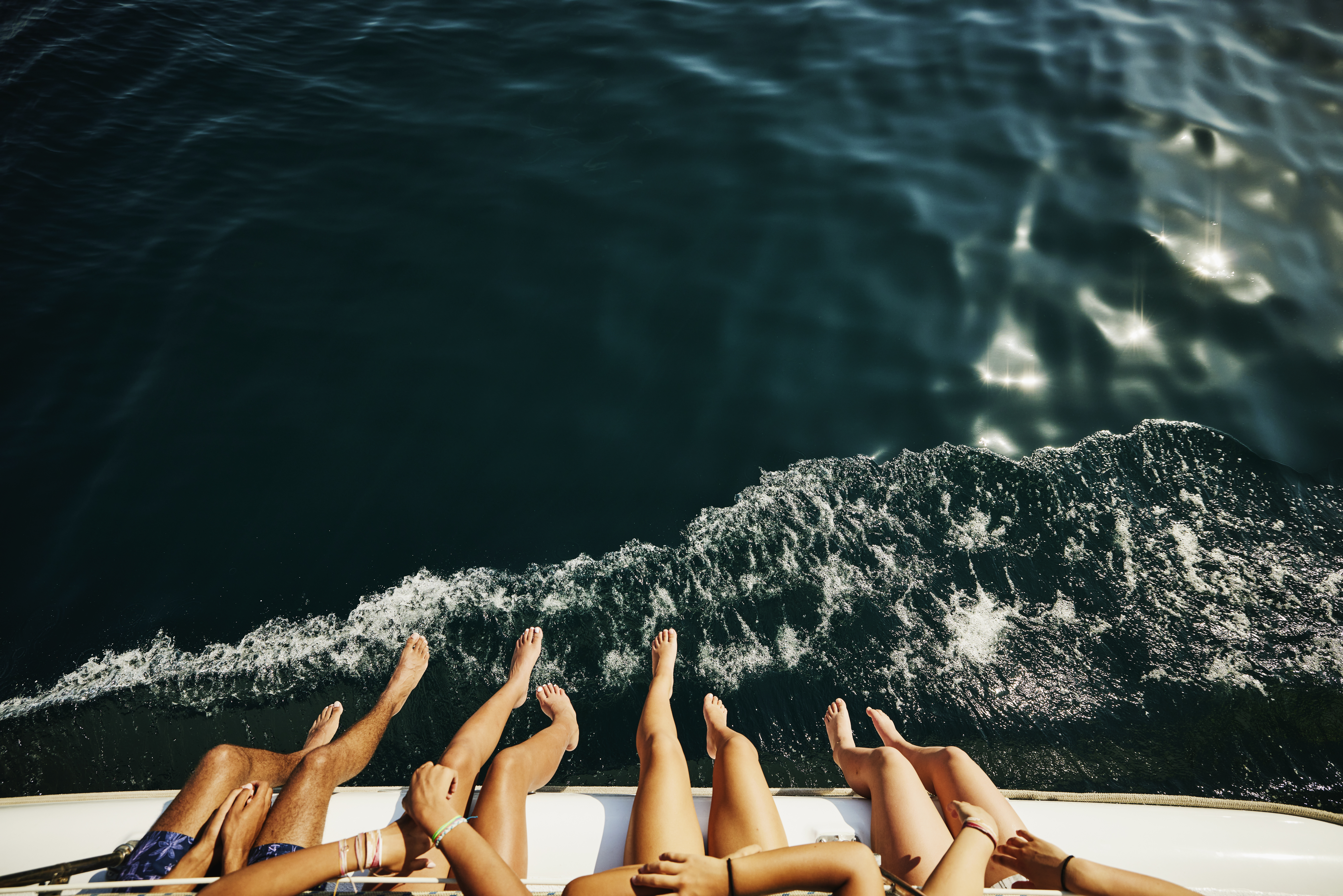 A shot of people dangling their legs over the edge of a boat | Source: Getty Images