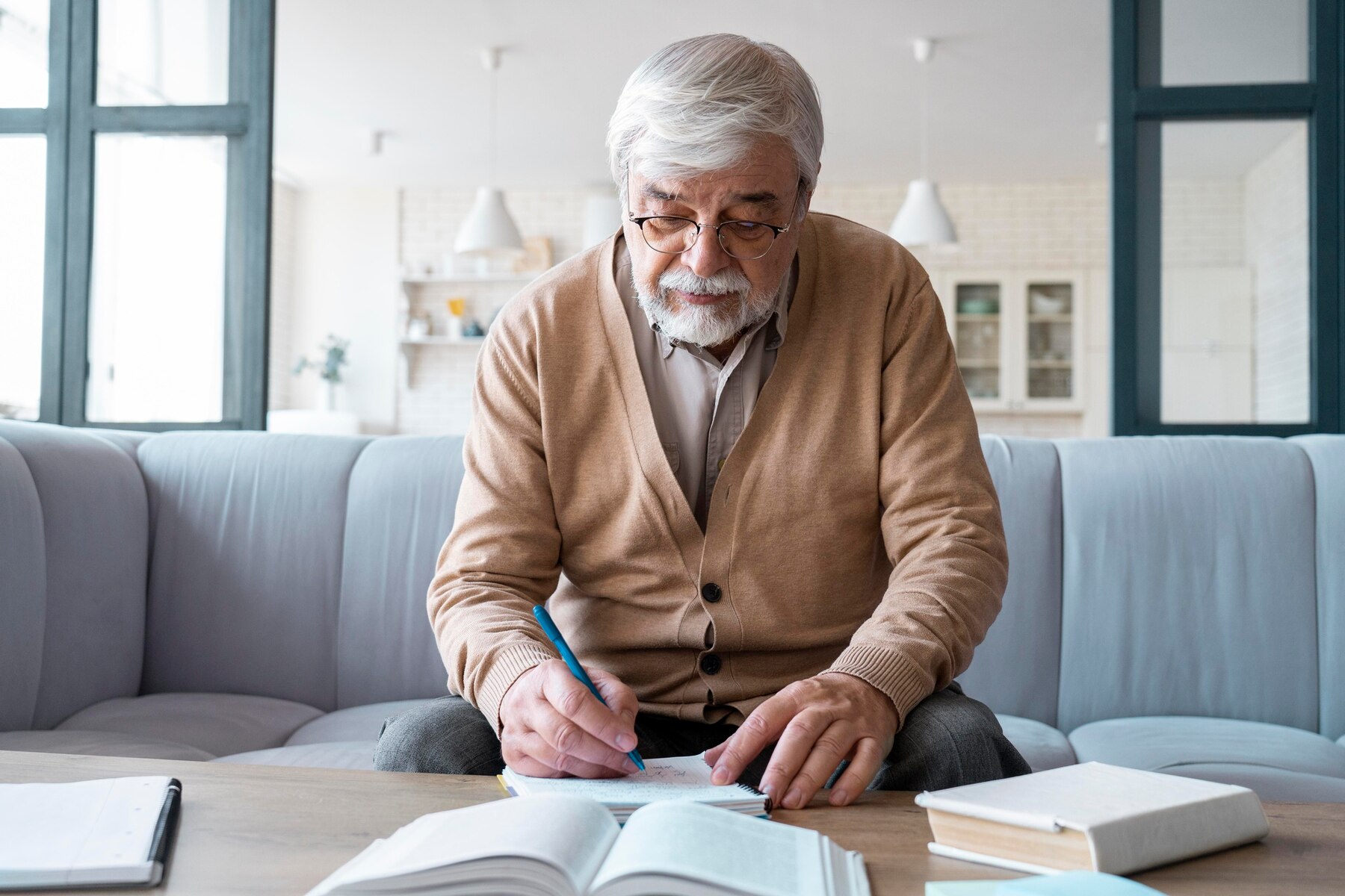 A senior man writing | Source: Freepik