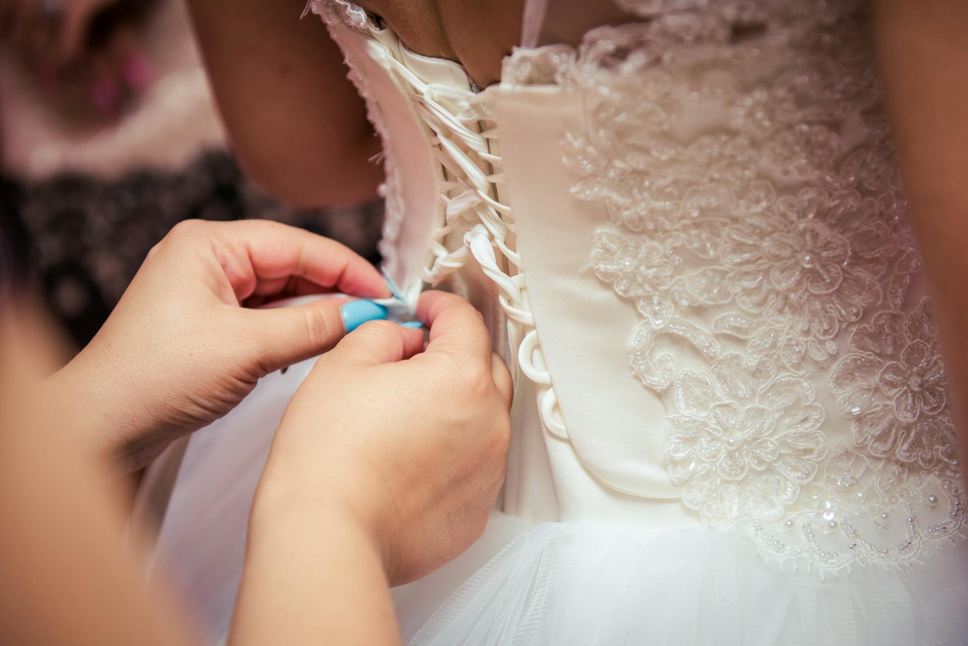 Close-up of a woman fixing a wedding gown | Source: Pexels