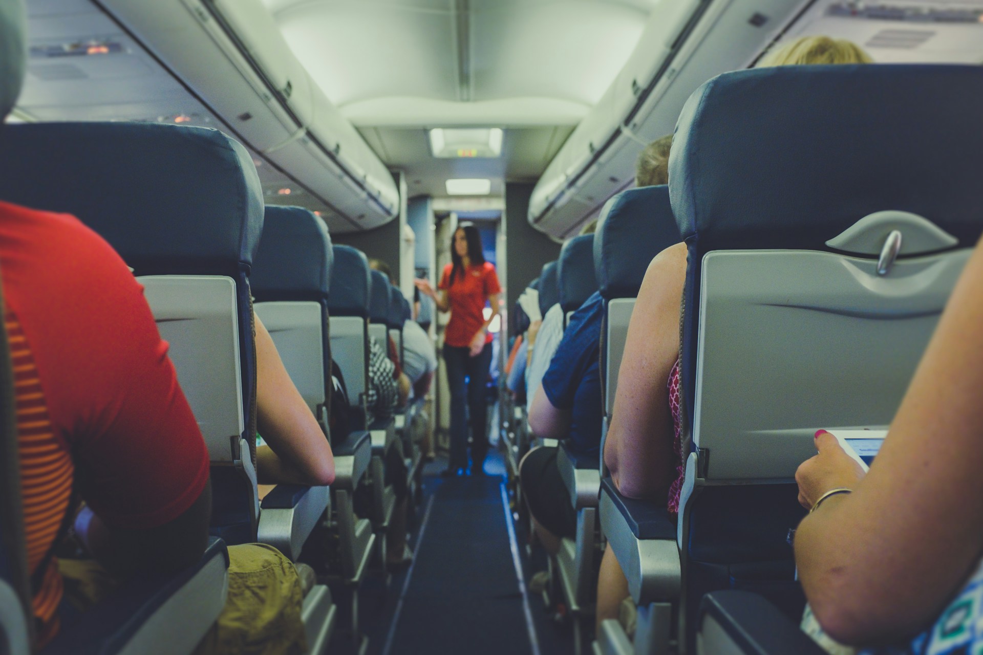 A flight attendant looking into passenger issues in the economy aisle | Source: Unsplash
