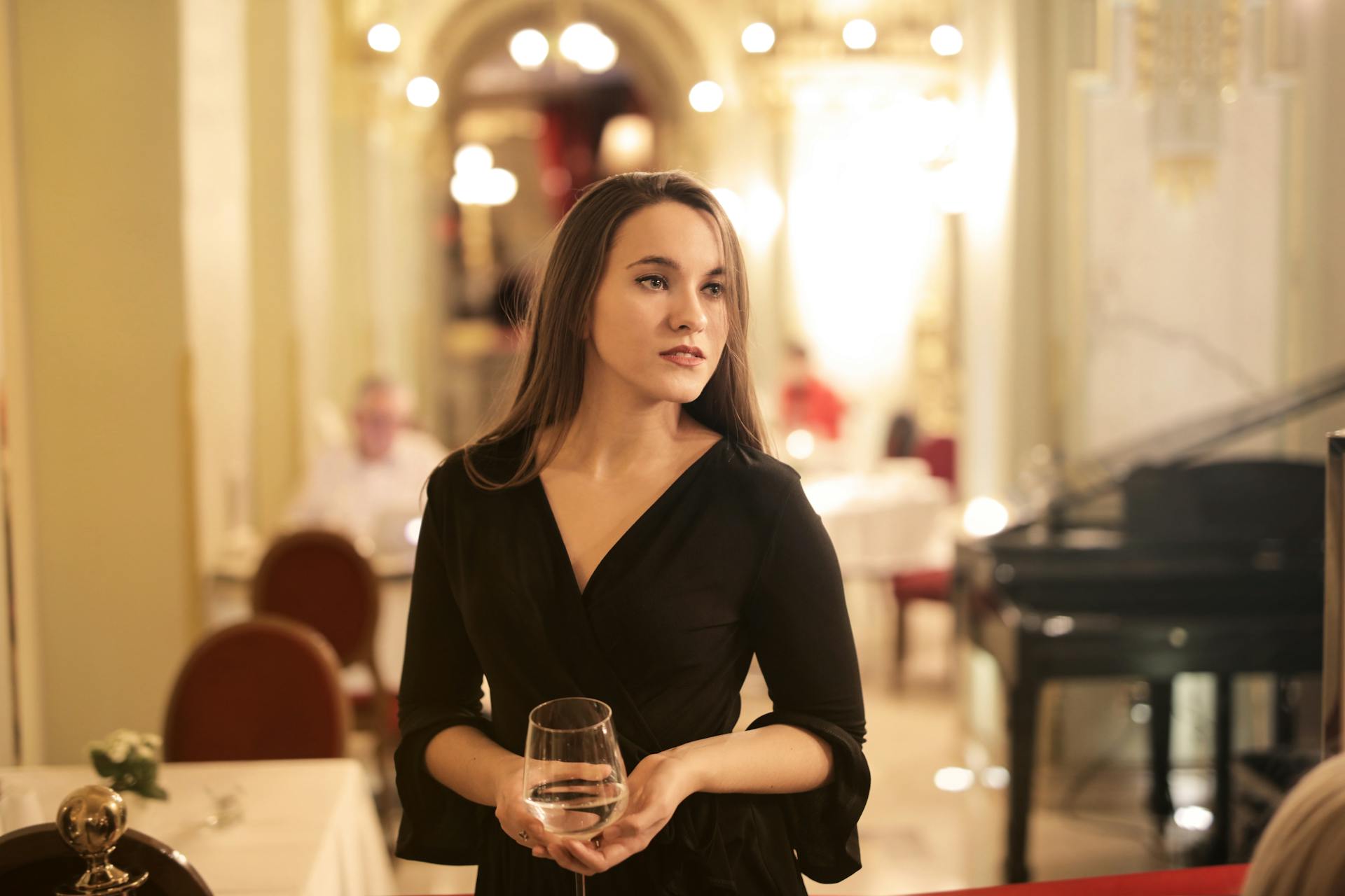 A woman holding a glass of drink while standing in a restaurant | Source: Pexels
