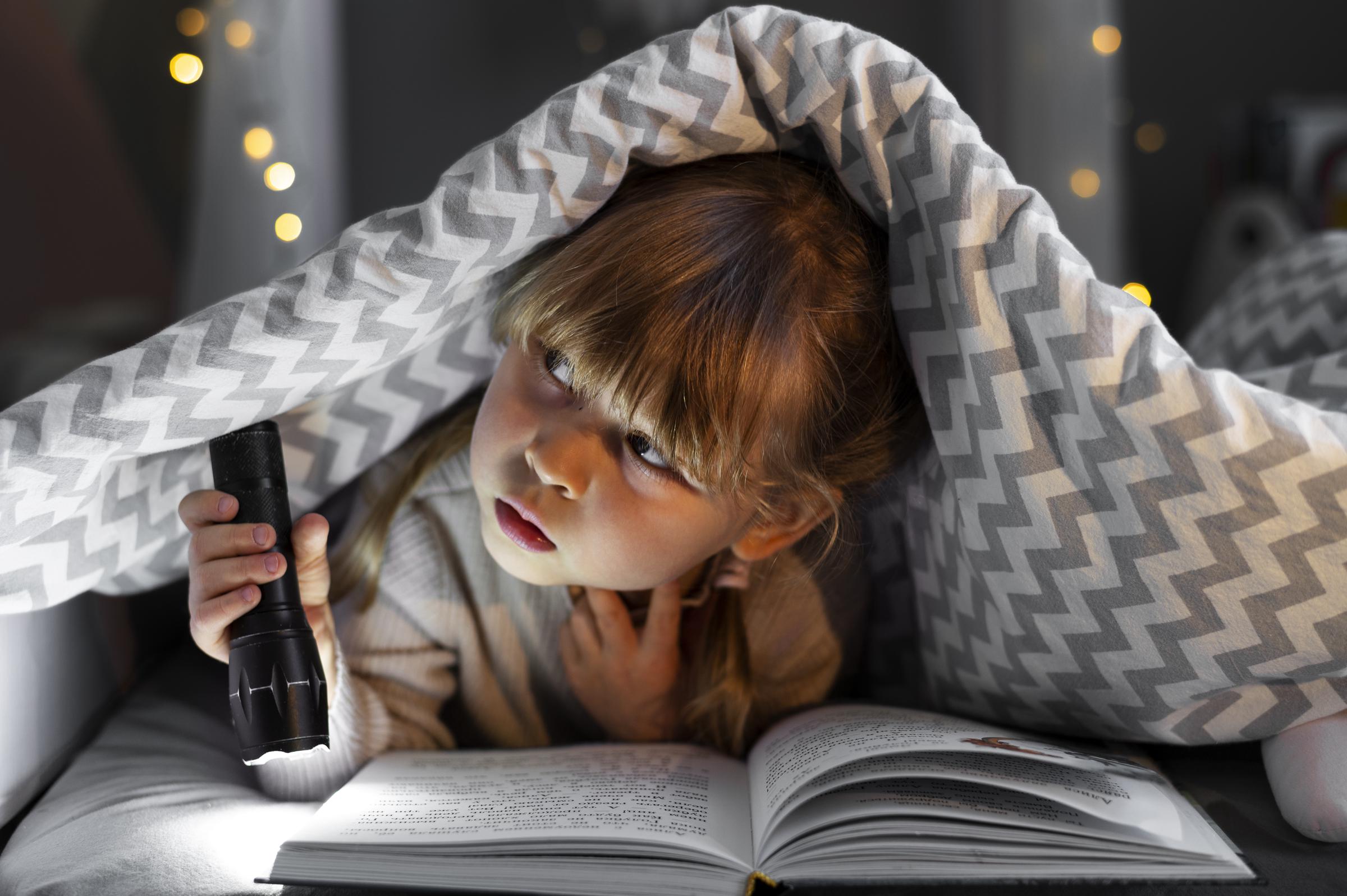 A little girl holding a flashlight | Source: Freepik