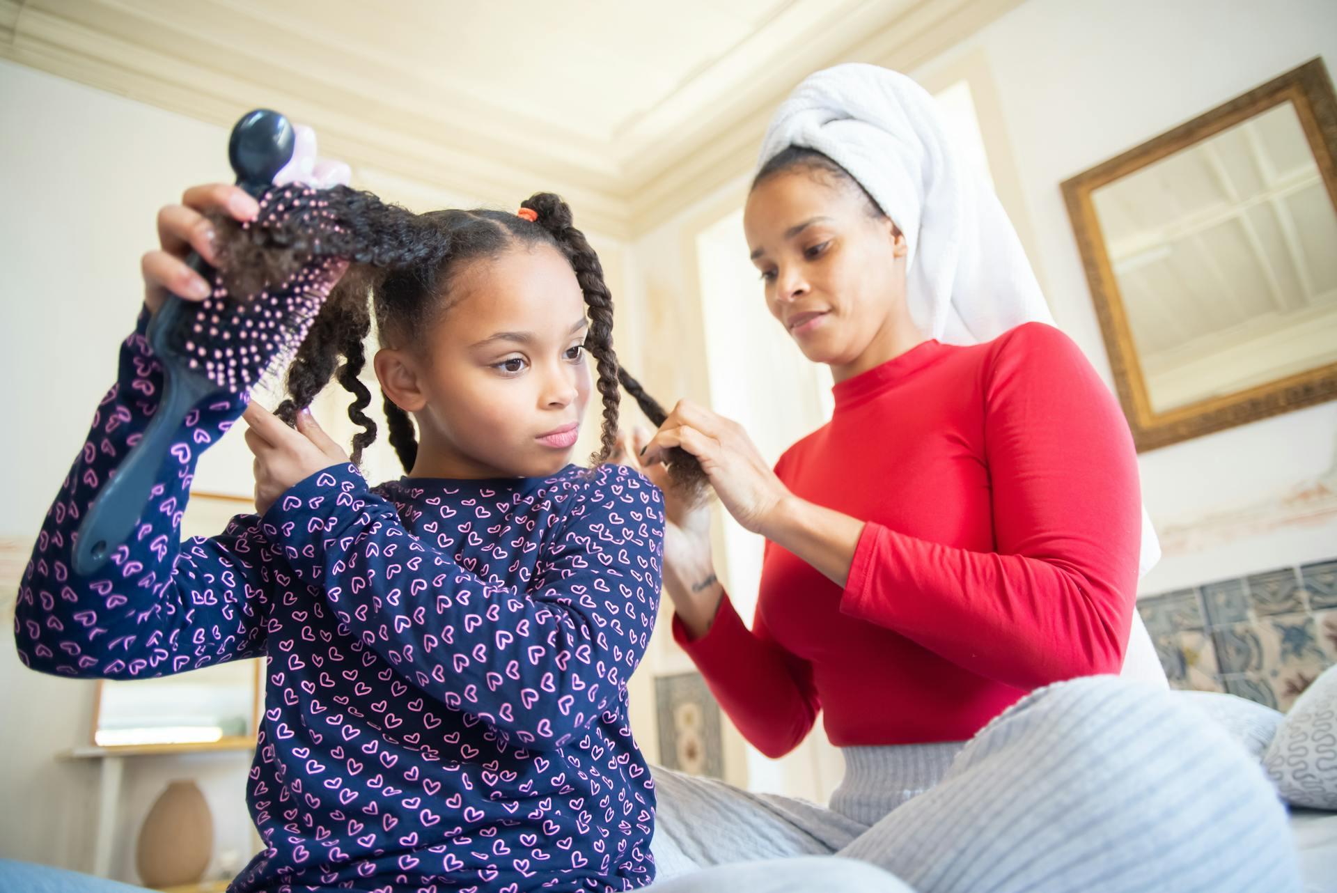 A mother braiding her daughter's hair | Source: Pexels