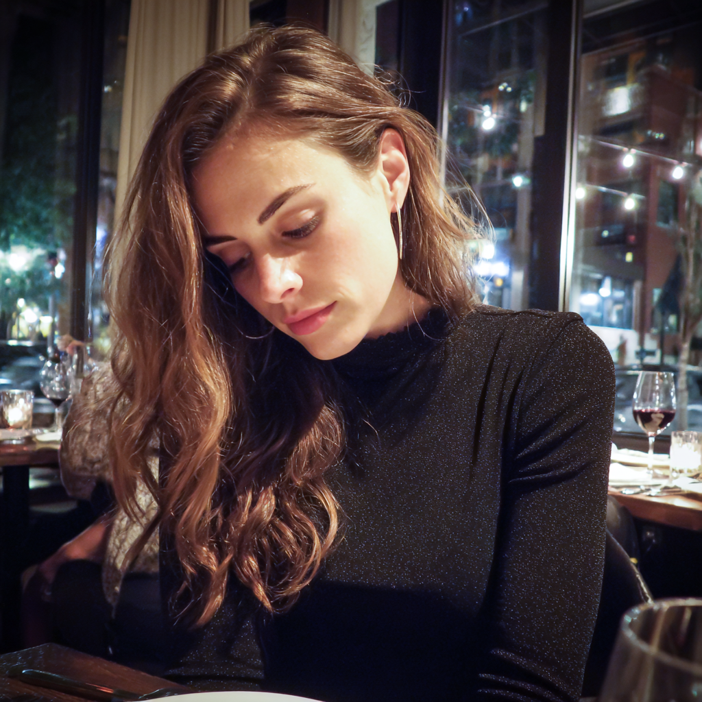 A woman looking down at her lap in a restaurant | Source: Midjourney