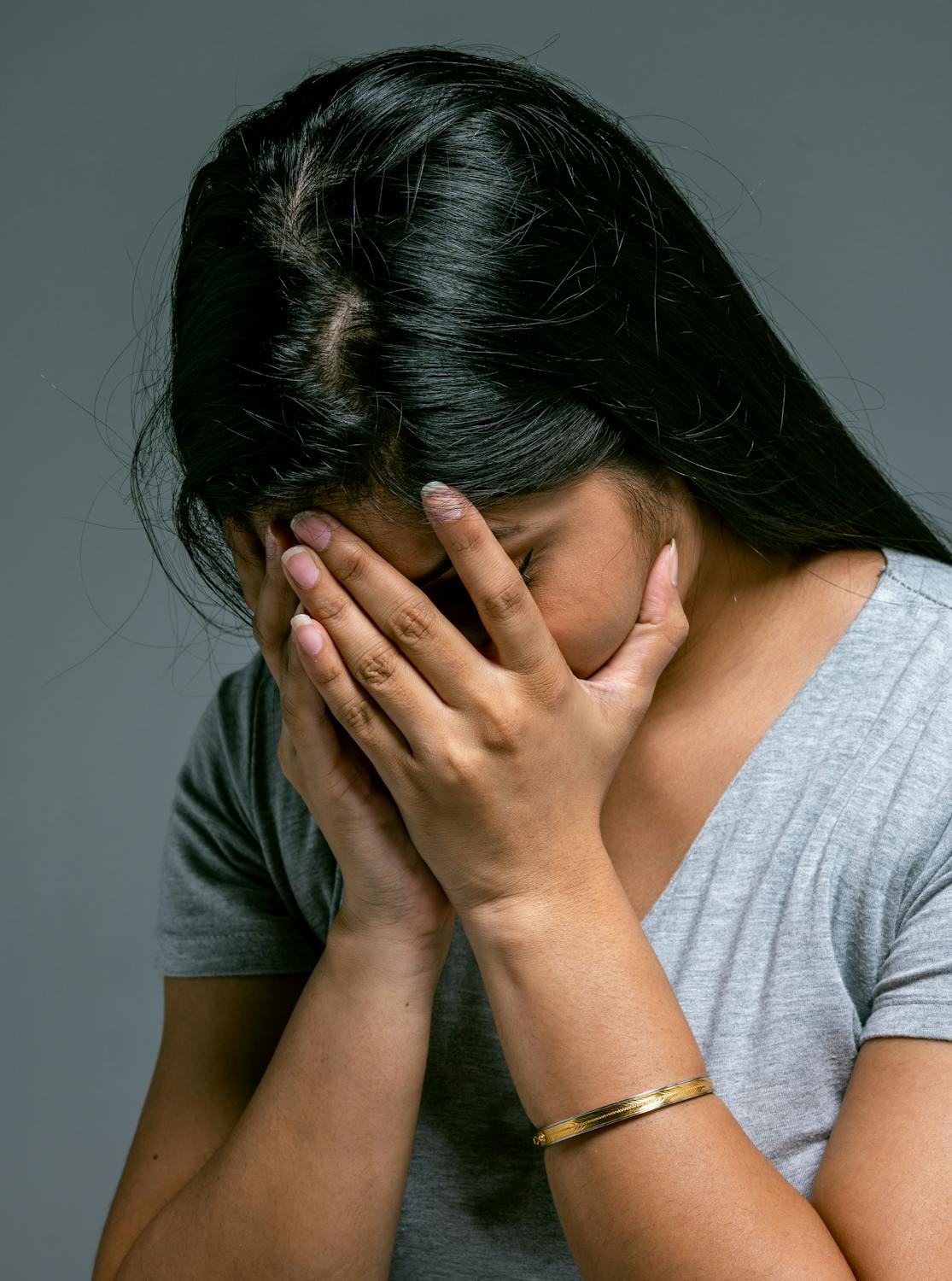 A crying woman hiding her face in her hands ⏐ Source: Pexels