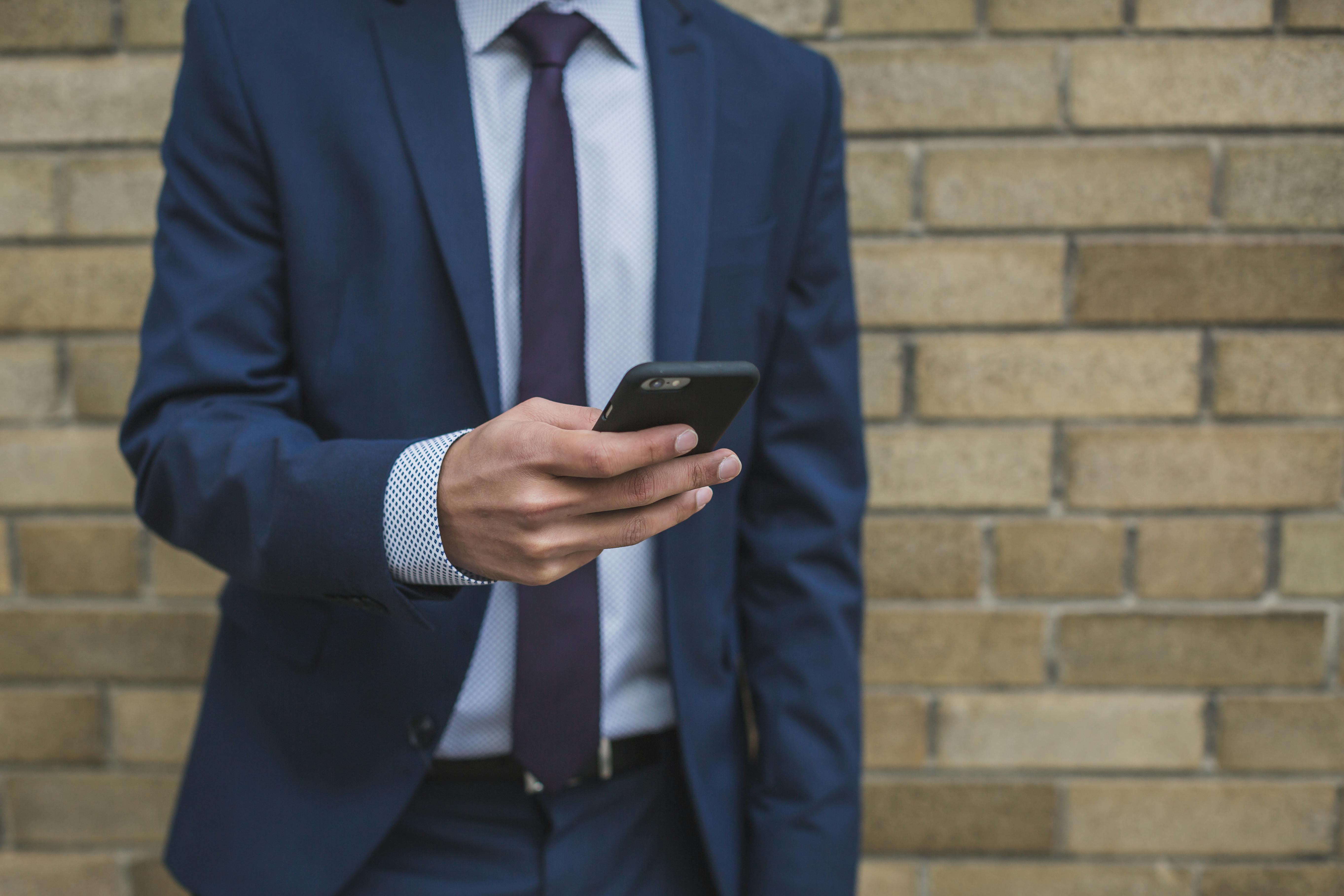 Man in a suit using his smartphone | Source: Pexels