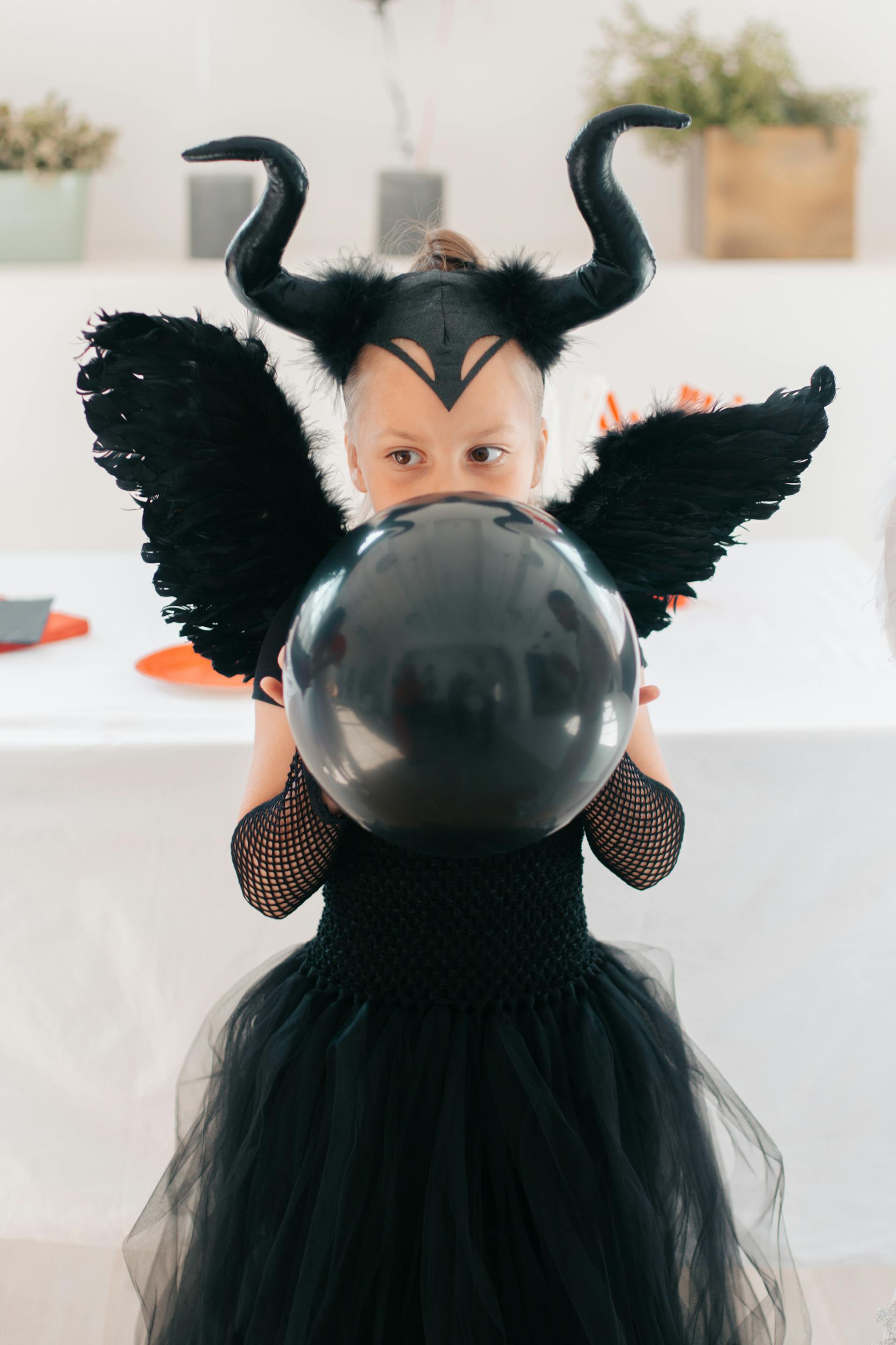 A young girl wearing a black Halloween costume and holding a balloon | Source: Pexels