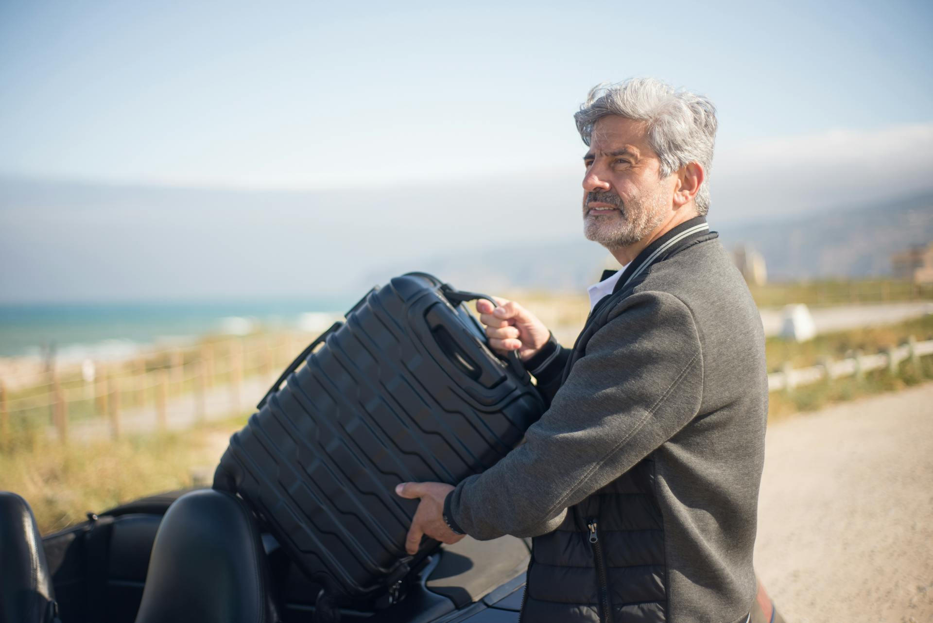 A man in a gray jacket holding a suitcase | Source: Pexels