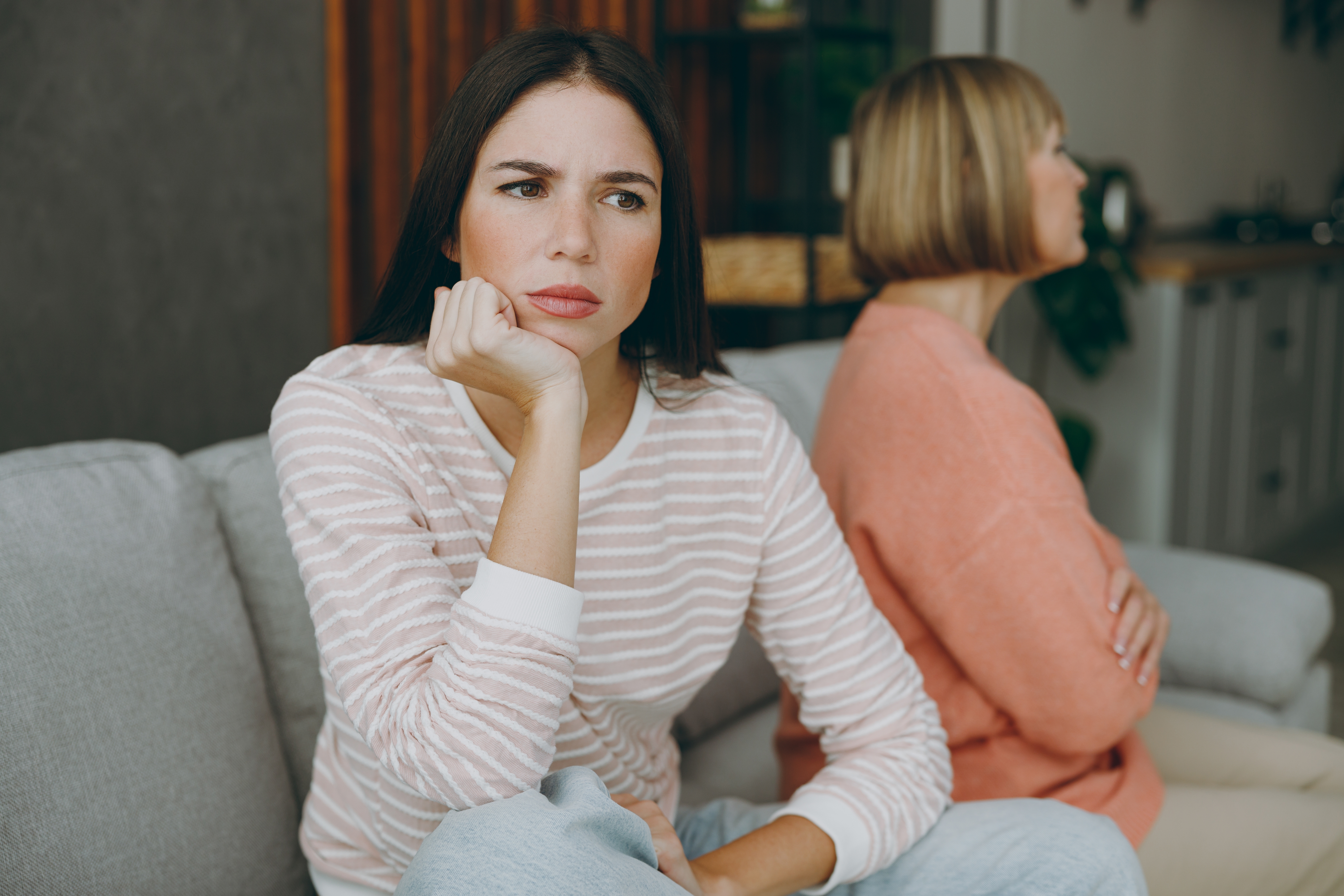 A senior woman and her daughter sitting apart after a disagreement | Source: Shutterstock