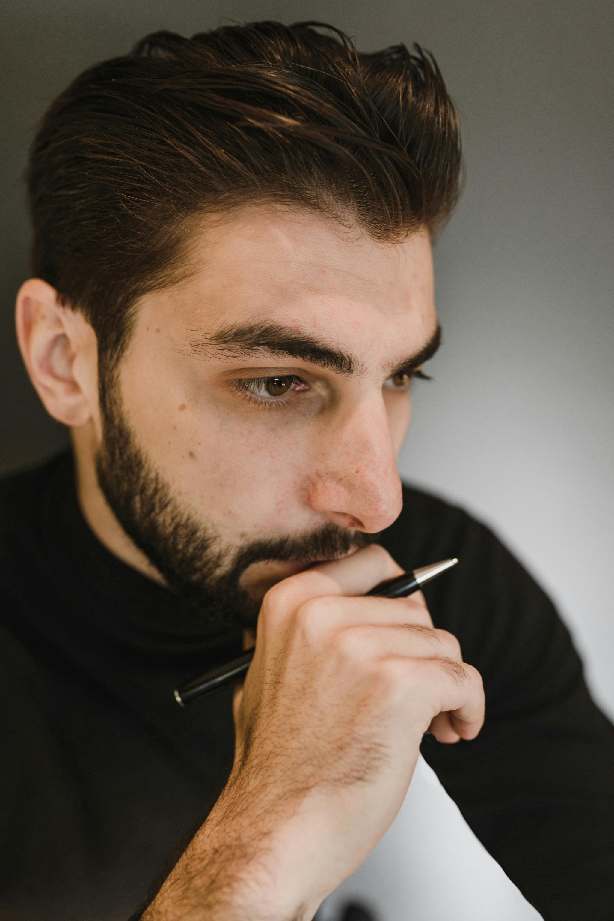 Man holding a pen while thinking | Source: Pexels