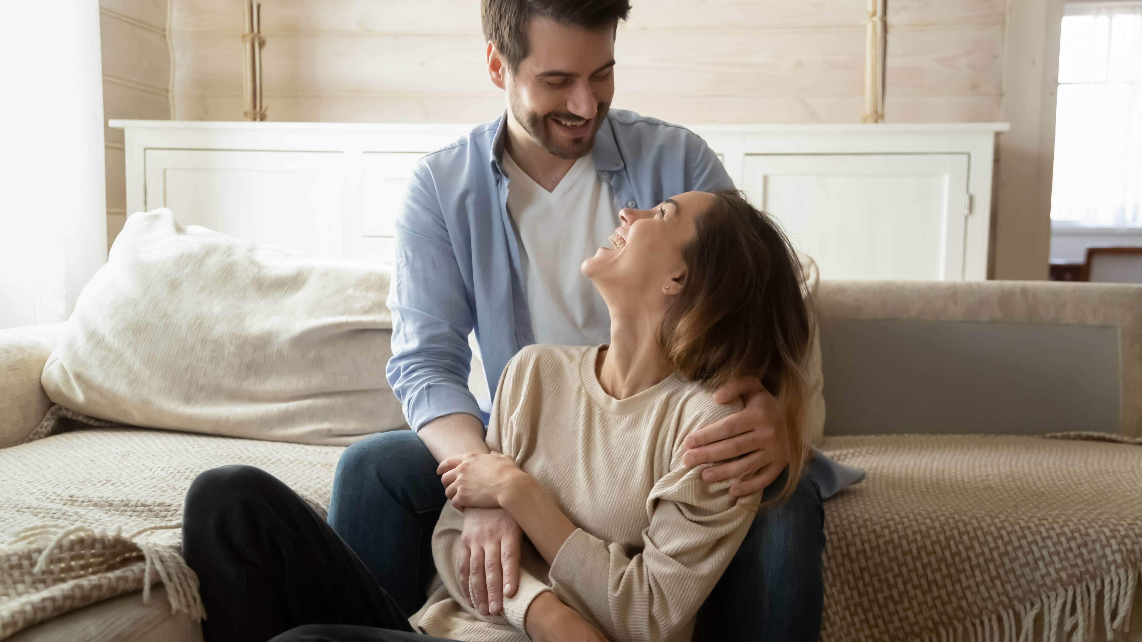 A couple holding hands and cuddling at home | Source: Shutterstock