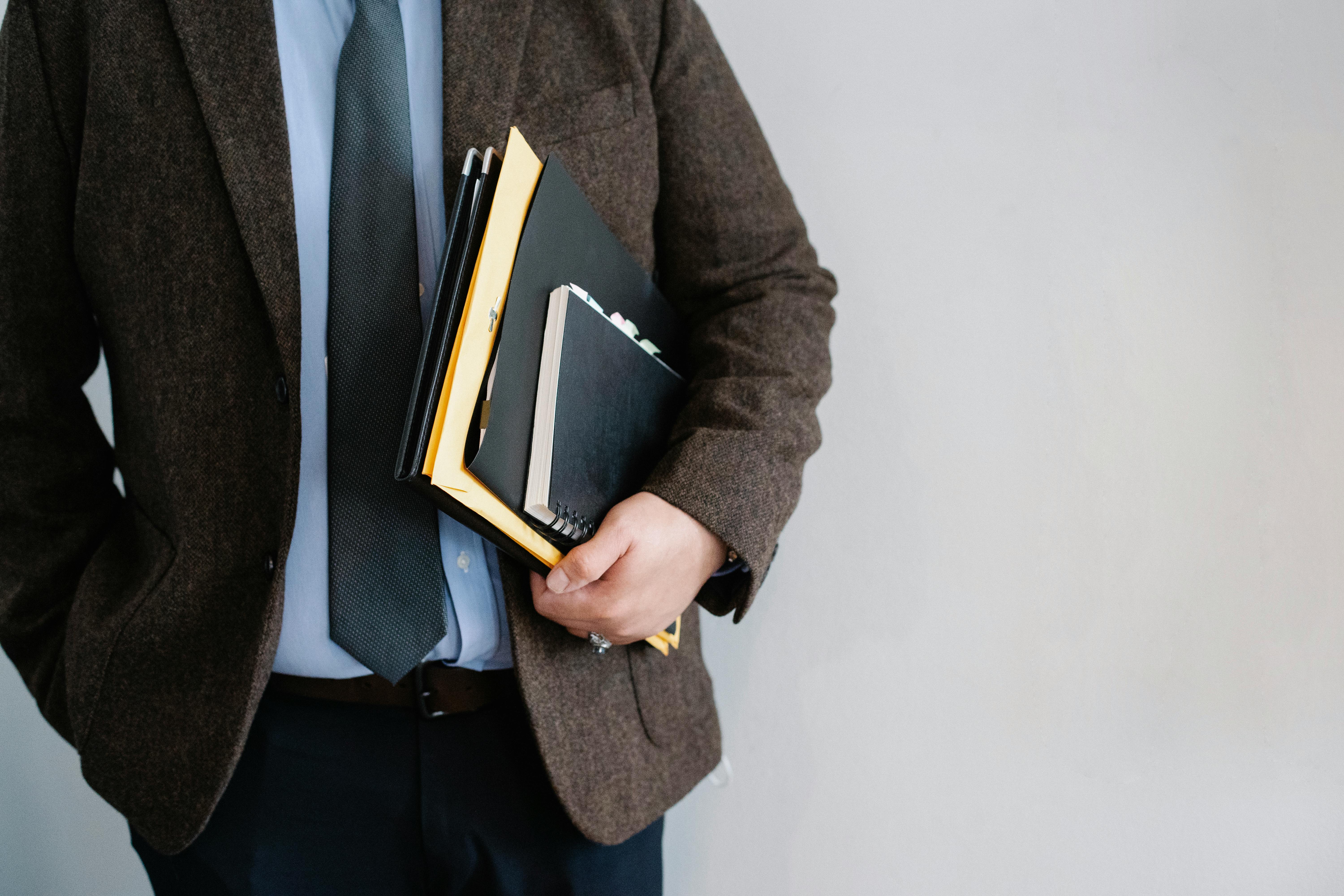 Cropped shot of a man holding a stack of folders | Source: Pexels