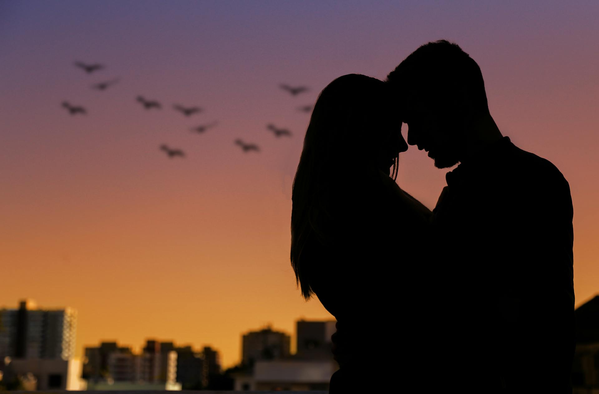 A couple silhouetted against a city skyline at sunset | Source: Pexels