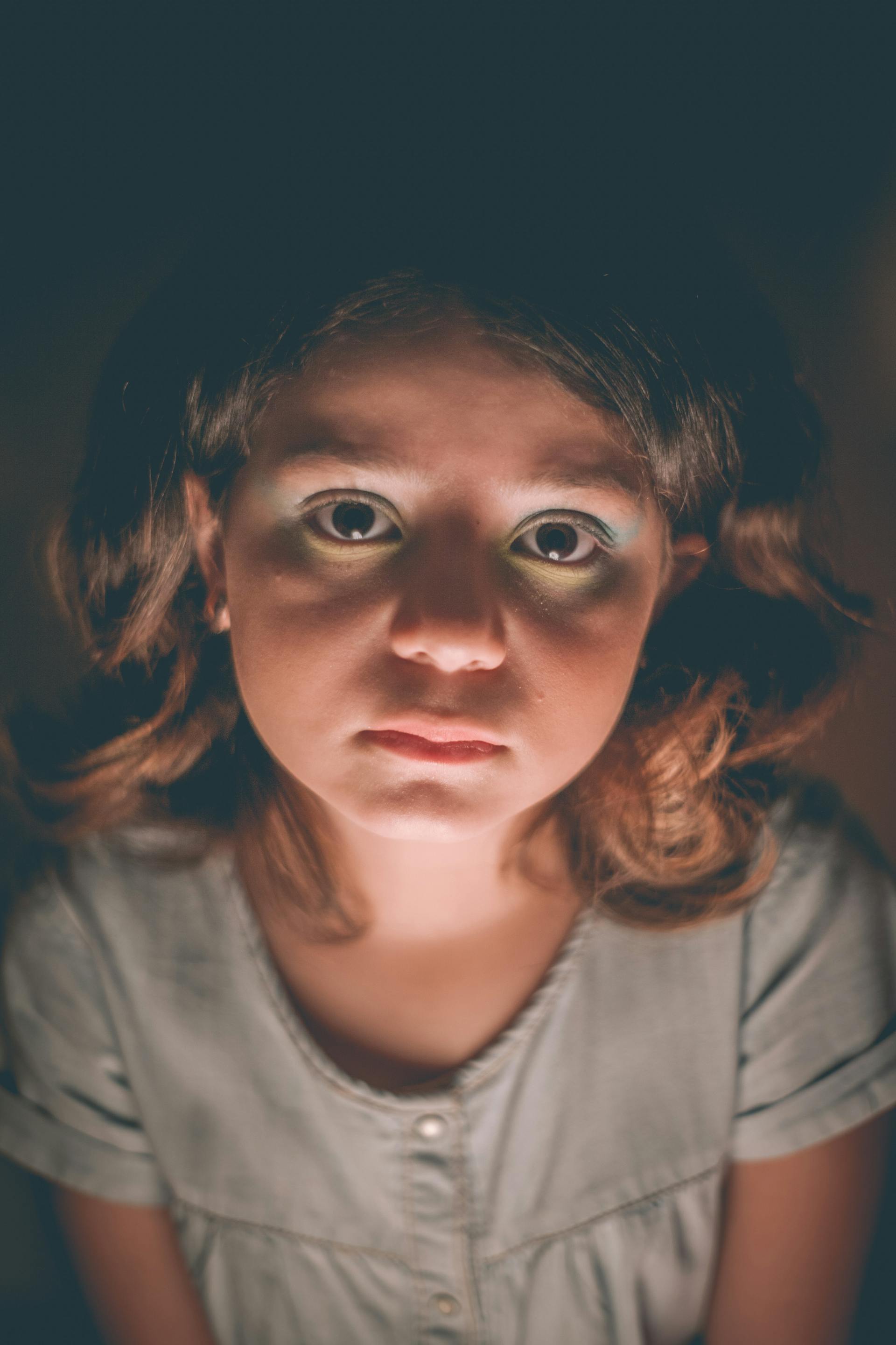 A sad-looking girl in a dark room | Source: Pexels