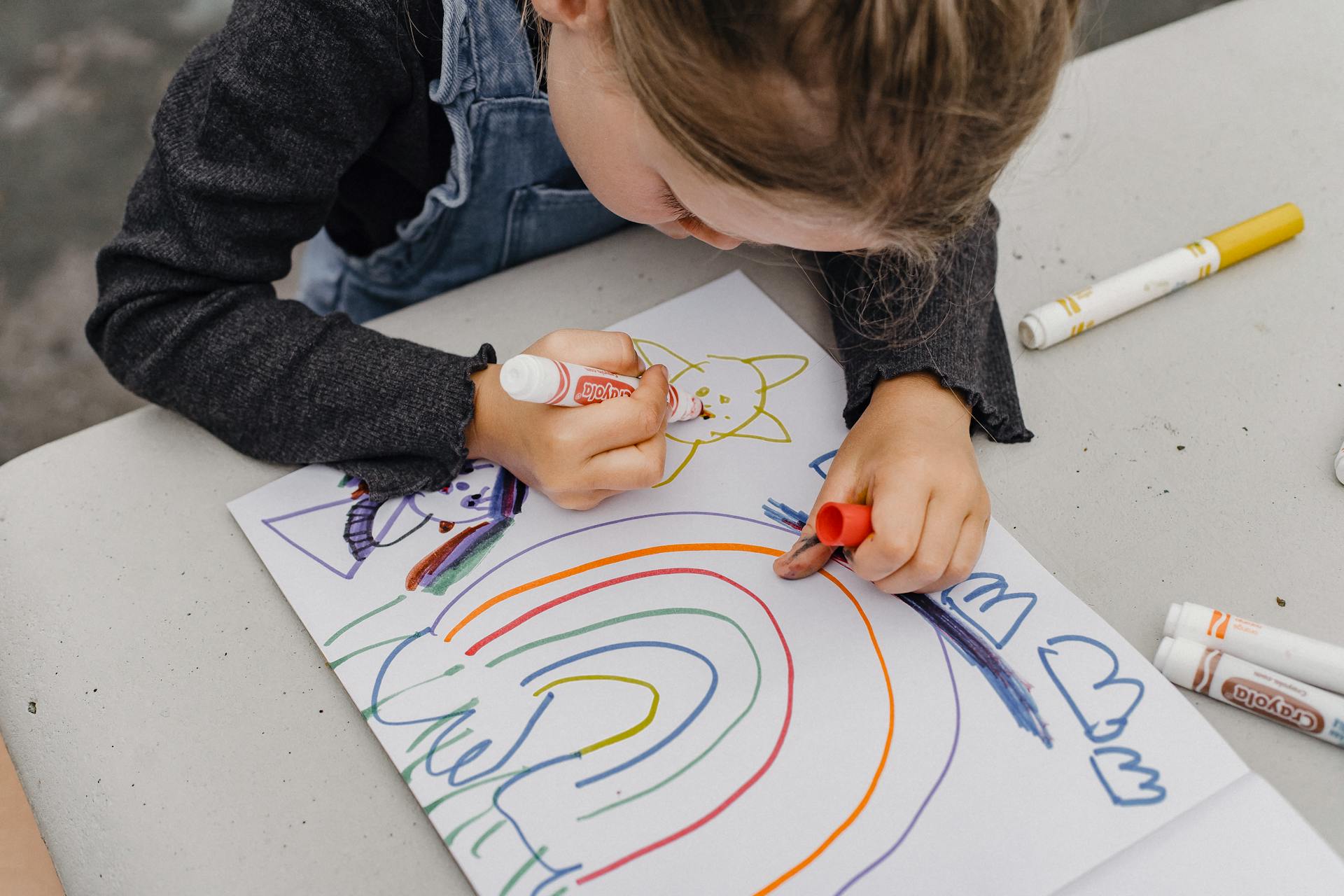 A close-up shot of a little girl drawing with markers on a paper | Source: Pexels