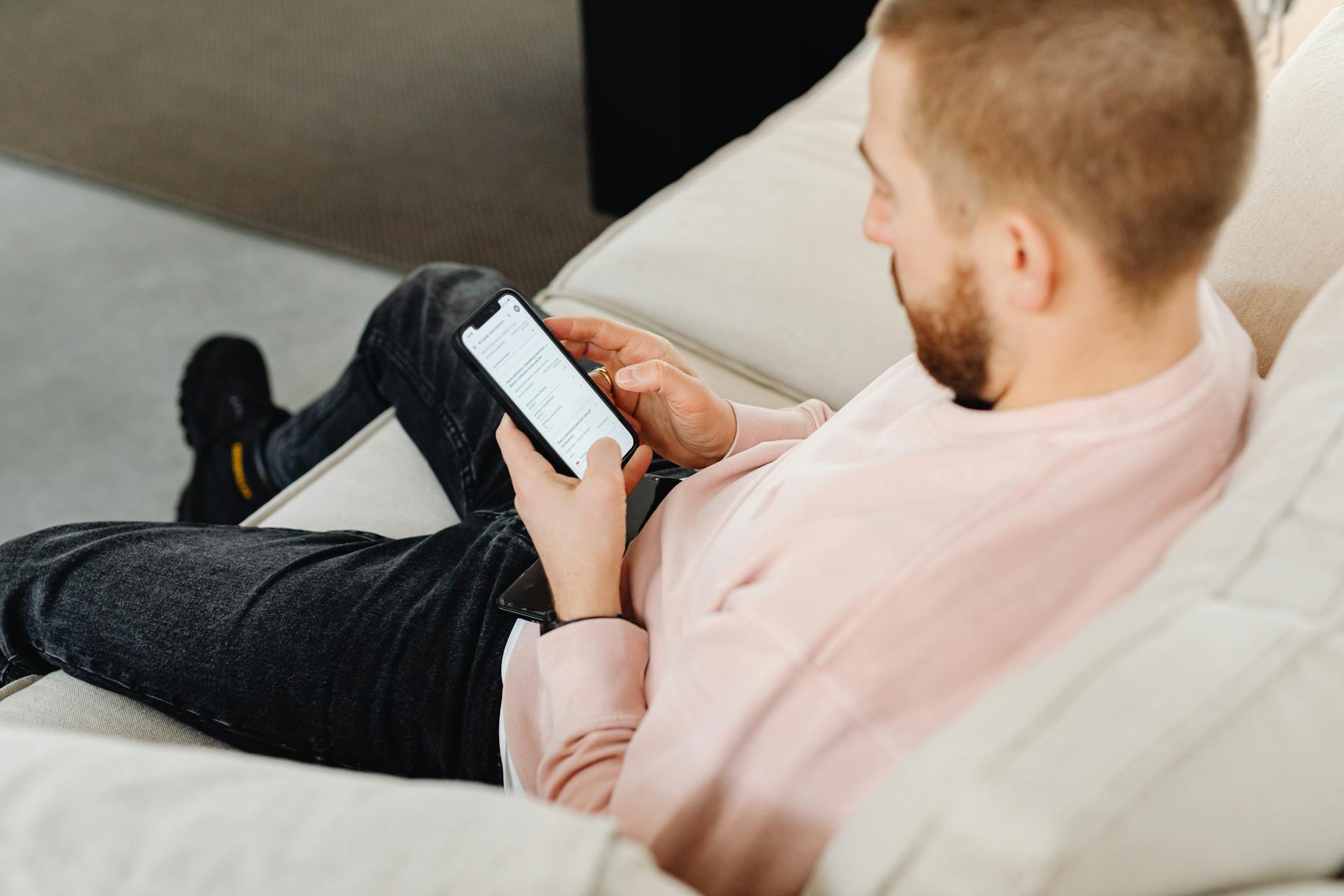 A man sitting on the couch and using his phone | Source: Pexels