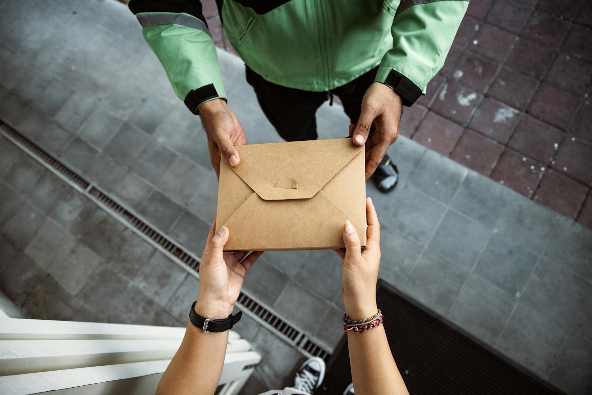 A mailman handing an envelope to a woman | Source: Pexels