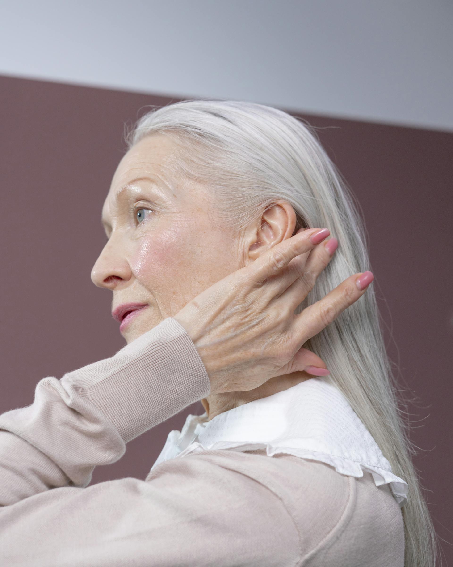 An elderly woman with a determined look touching her hair | Source: Pexels