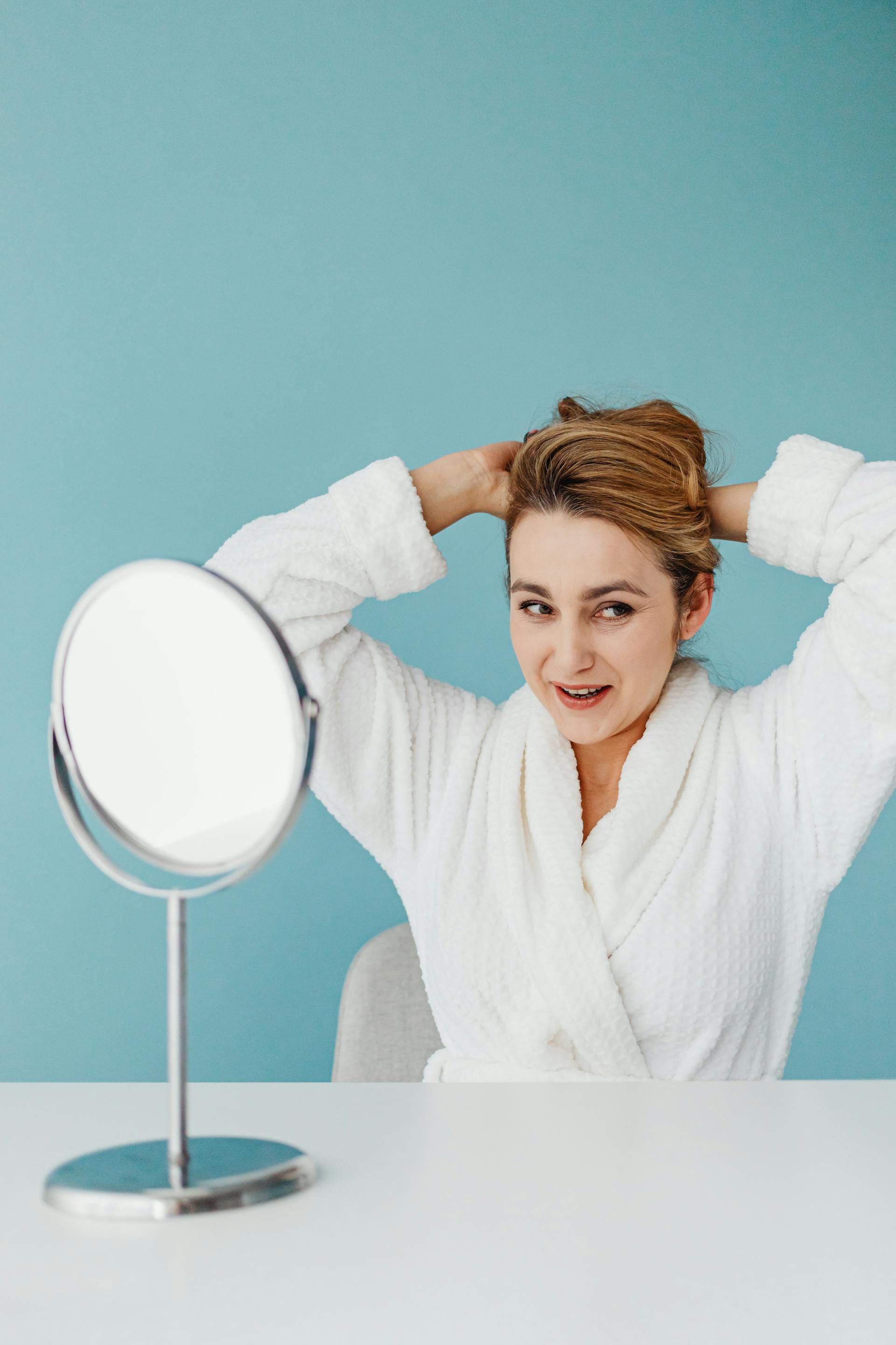 A smiling woman doing her hair | Source: Pexels
