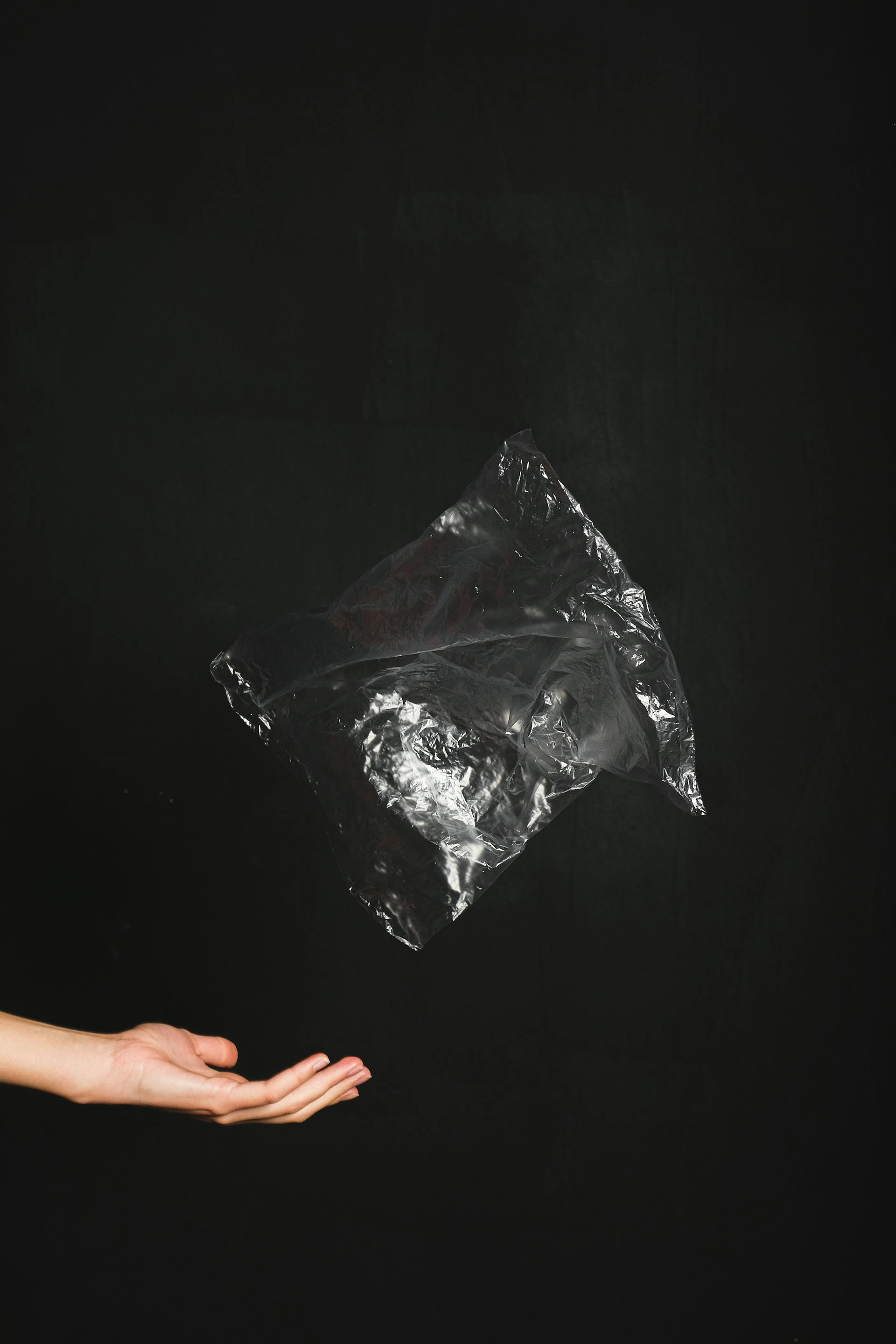 A close-up shot of a hand throwing a black plastic bag | Source: Pexels