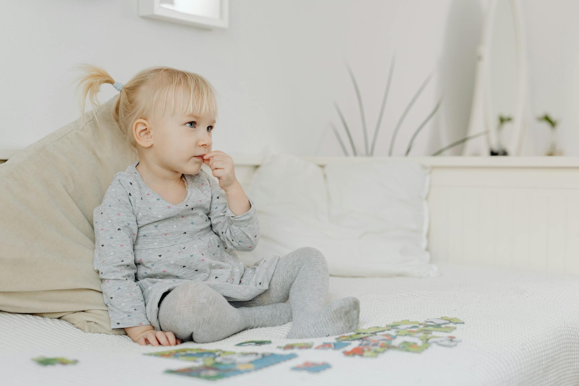 A little girl sitting alone while playing with a puzzle | Source: Pexels