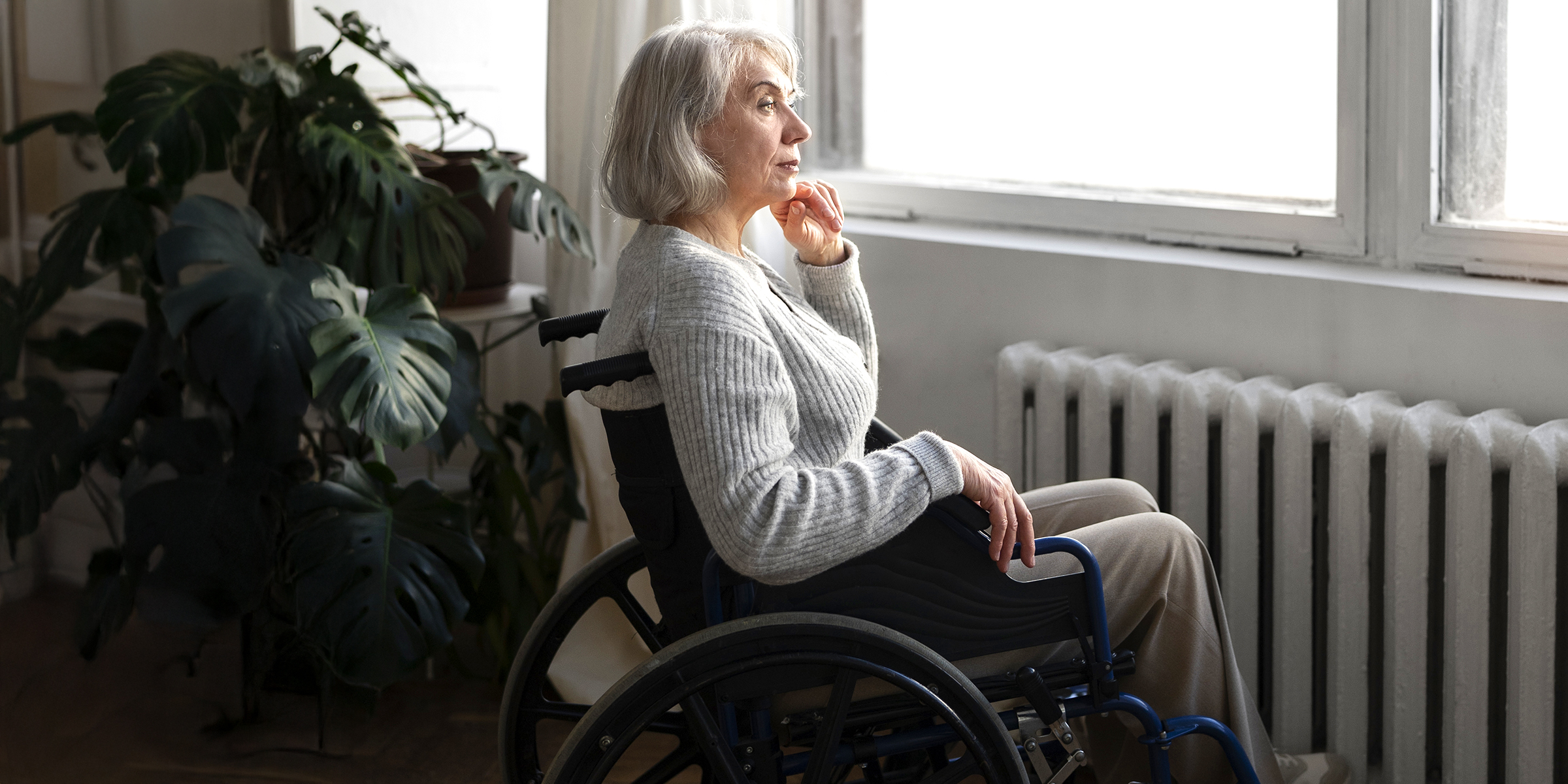 An elderly woman staring out a window | Source: Freepik