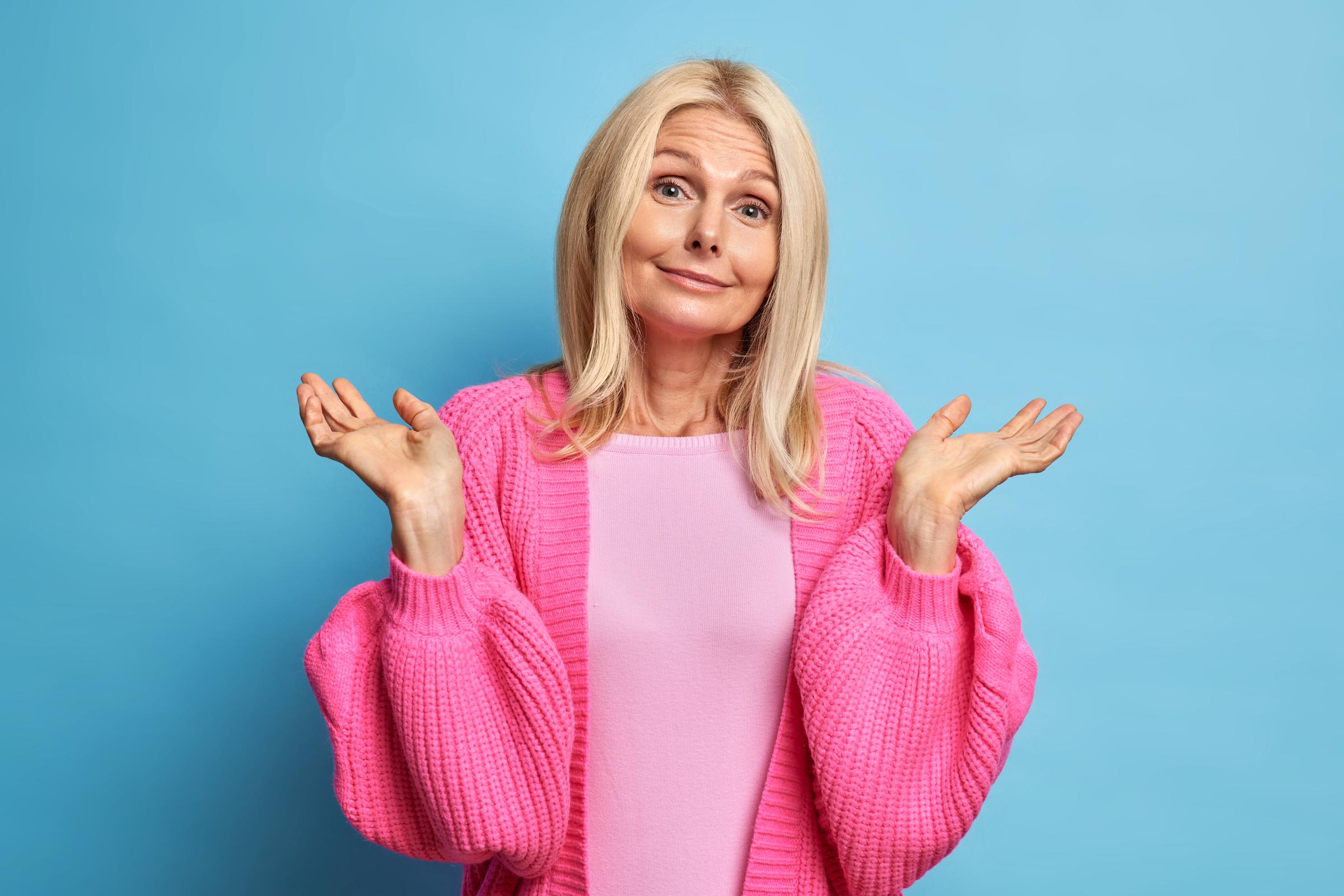A senior woman shrugging with indifference | Source: Freepik