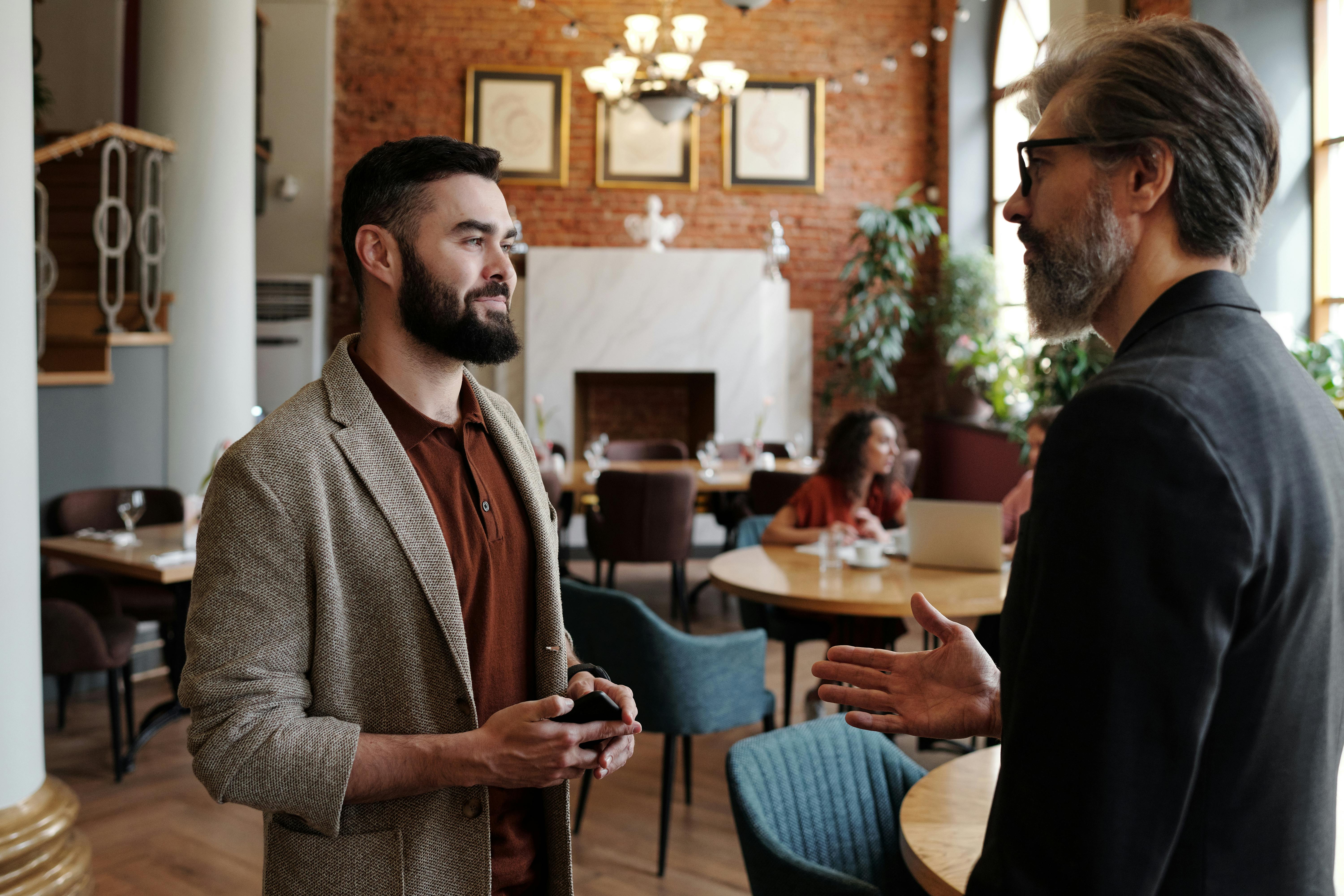 Senior man in black jacket talking to a man in brown jacket | Source: Pexels