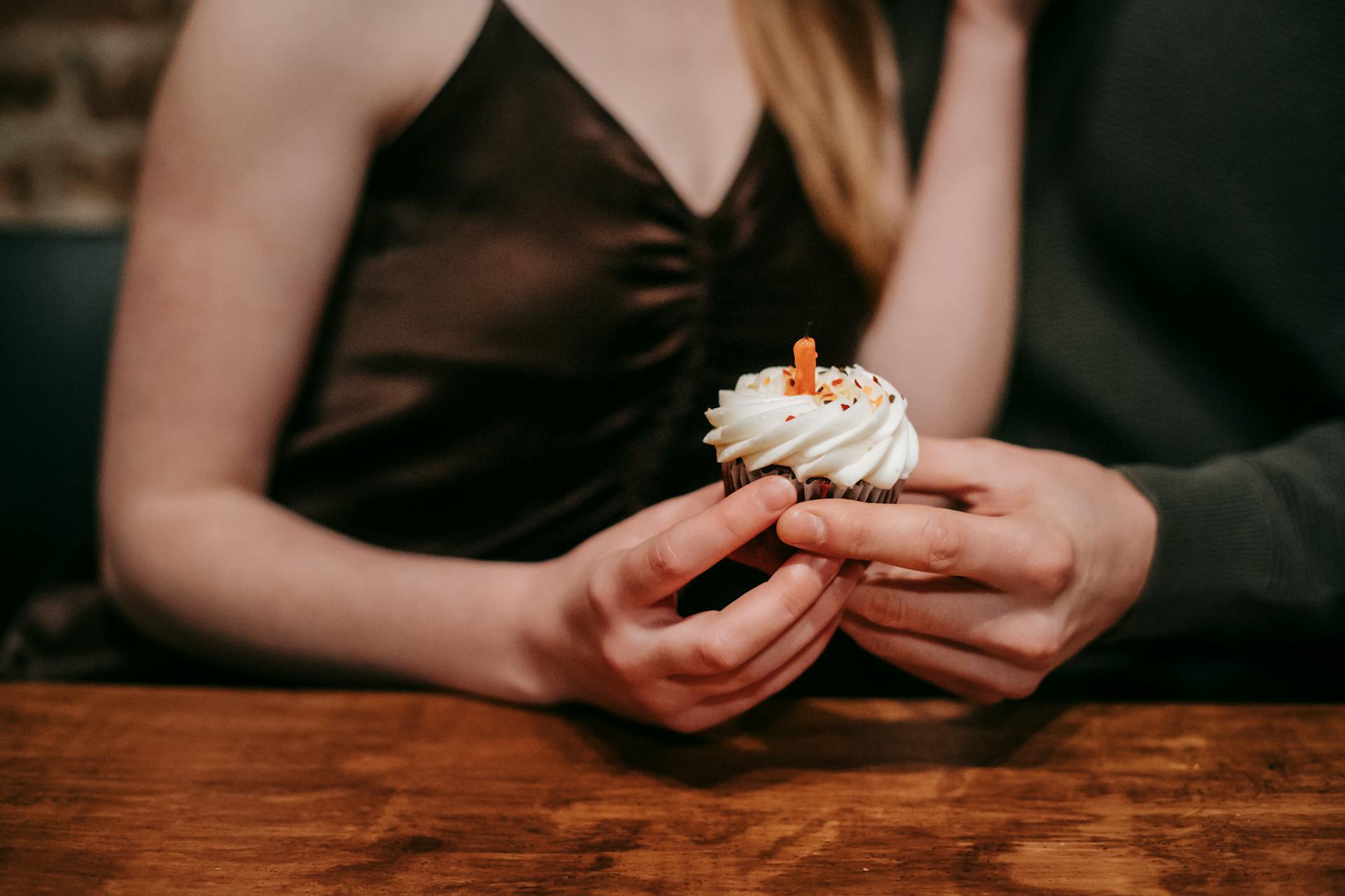 A close-up shot of a couple holding a cupcake in a café | Source: Pexels