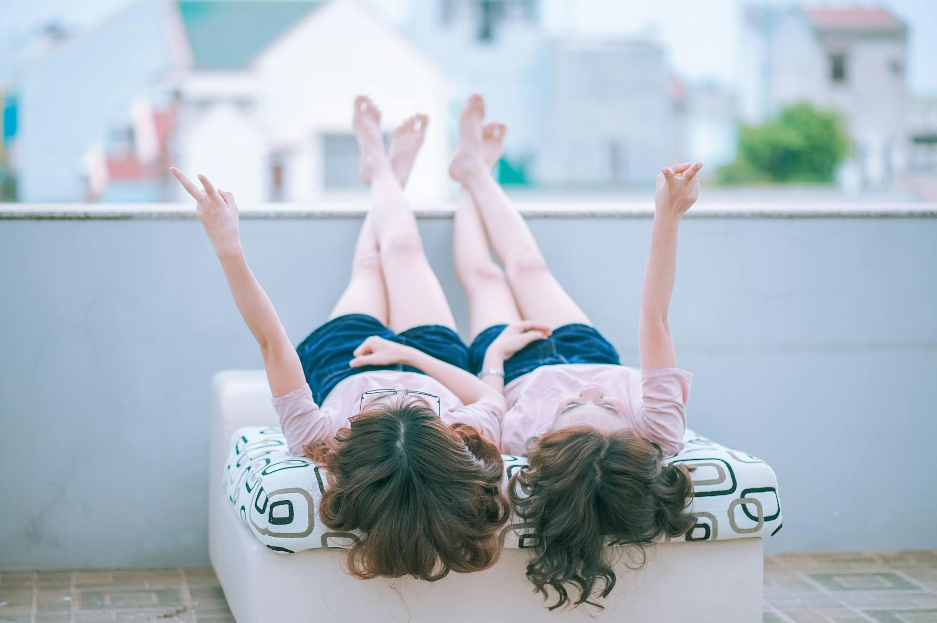 Two young women lying on a balcony and flashing peace signs | Source: Pexels